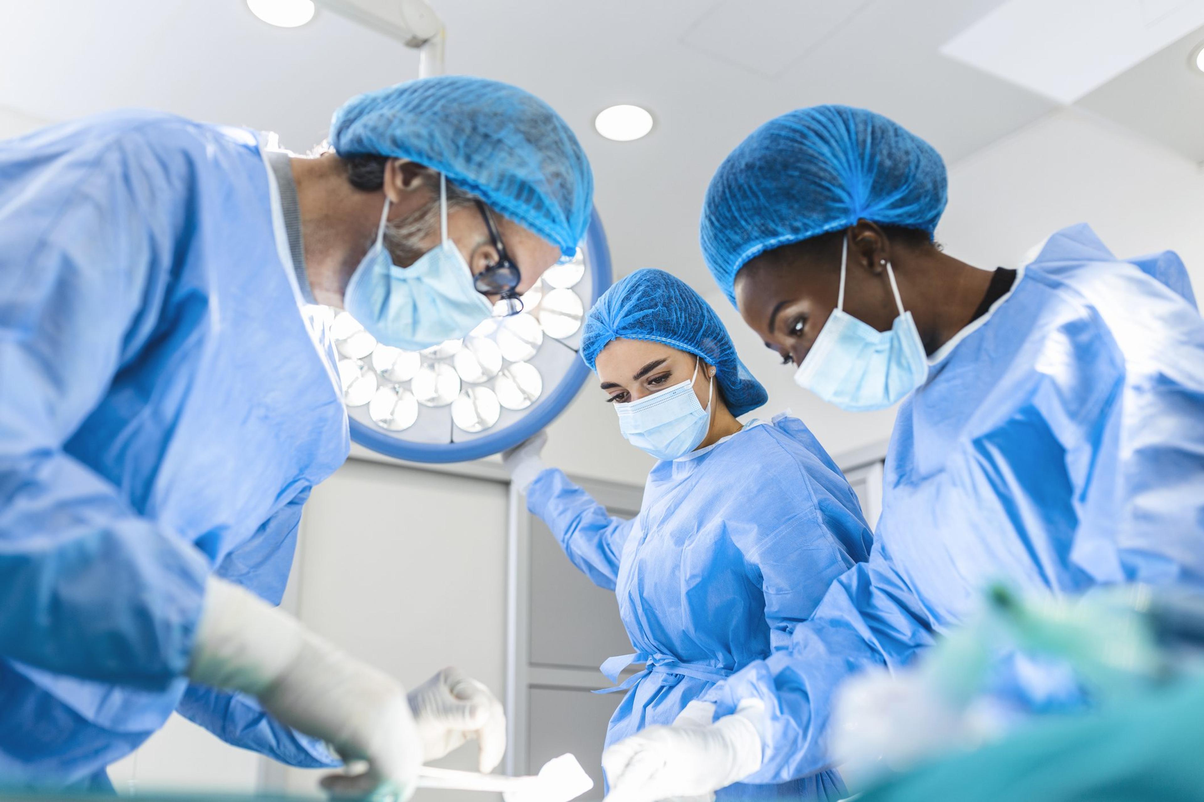 Surgeons wearing protective equipment prepare for a surgery