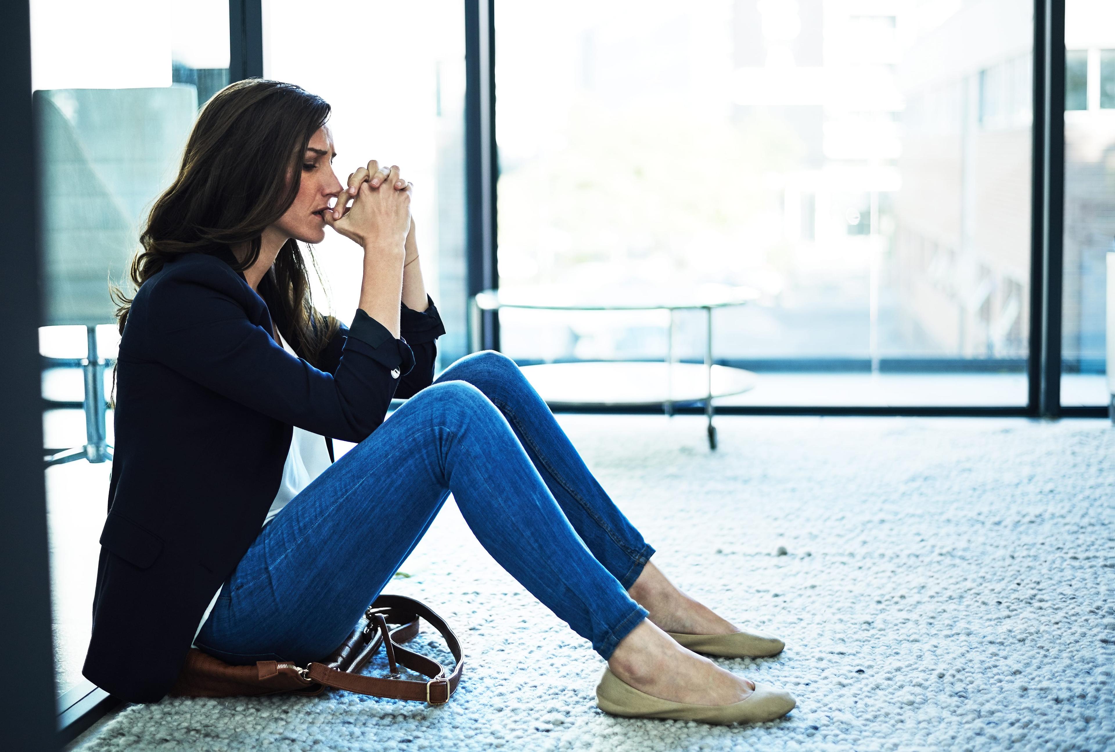 Shot of a stressed businesswoman sitting on the floor outside the boardroom