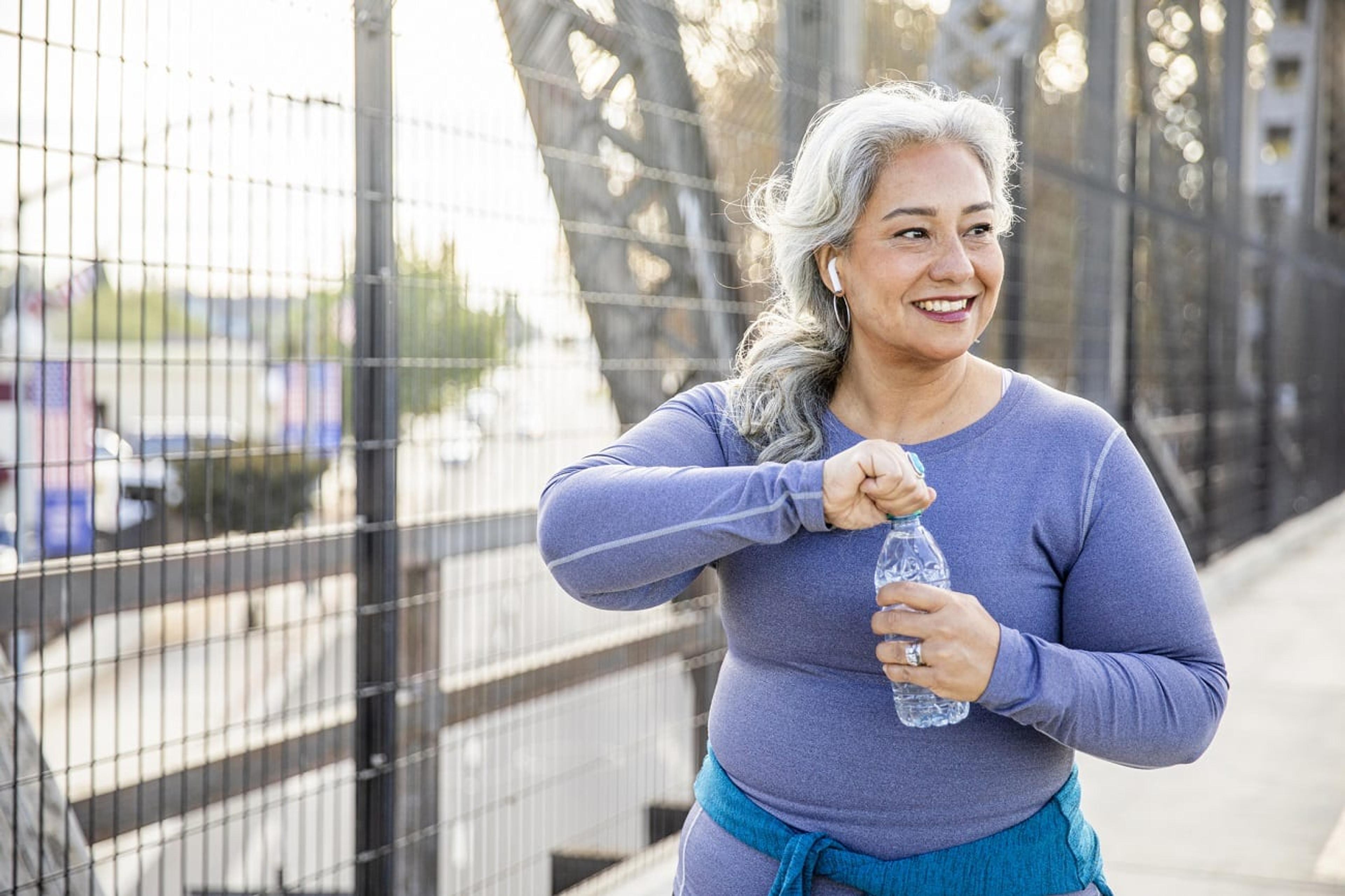 Woman holds a water bottle while on a walk