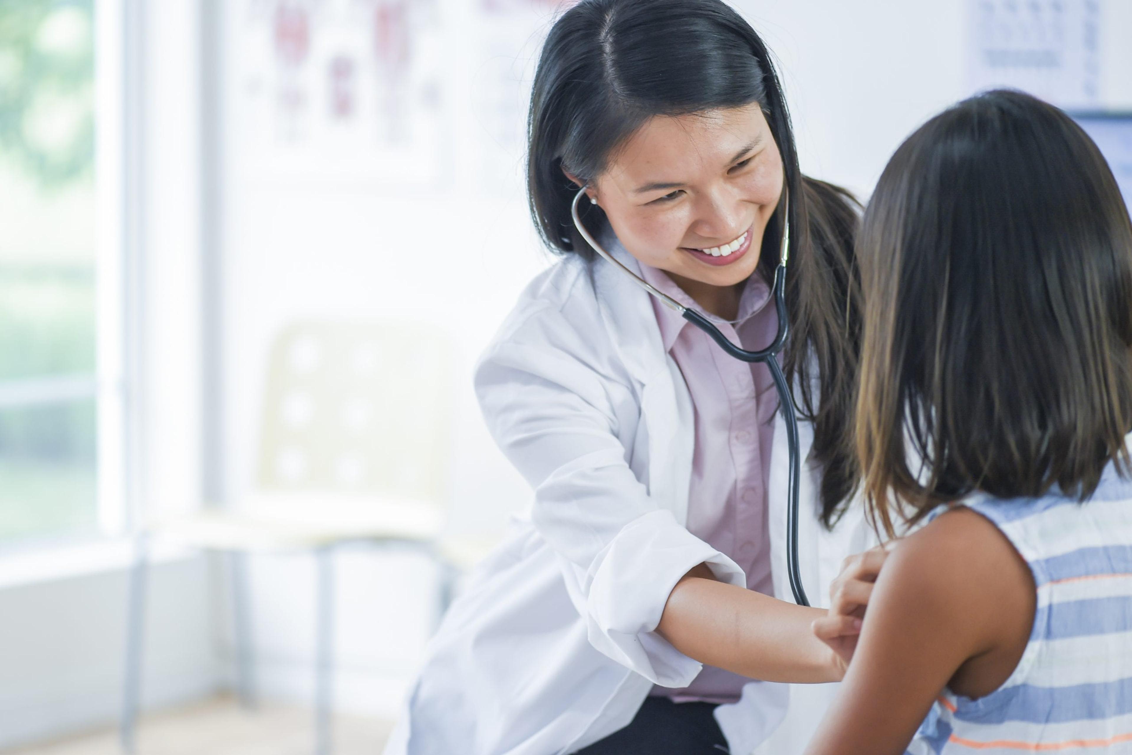 Female doctor checking a young patient's heartbeat.