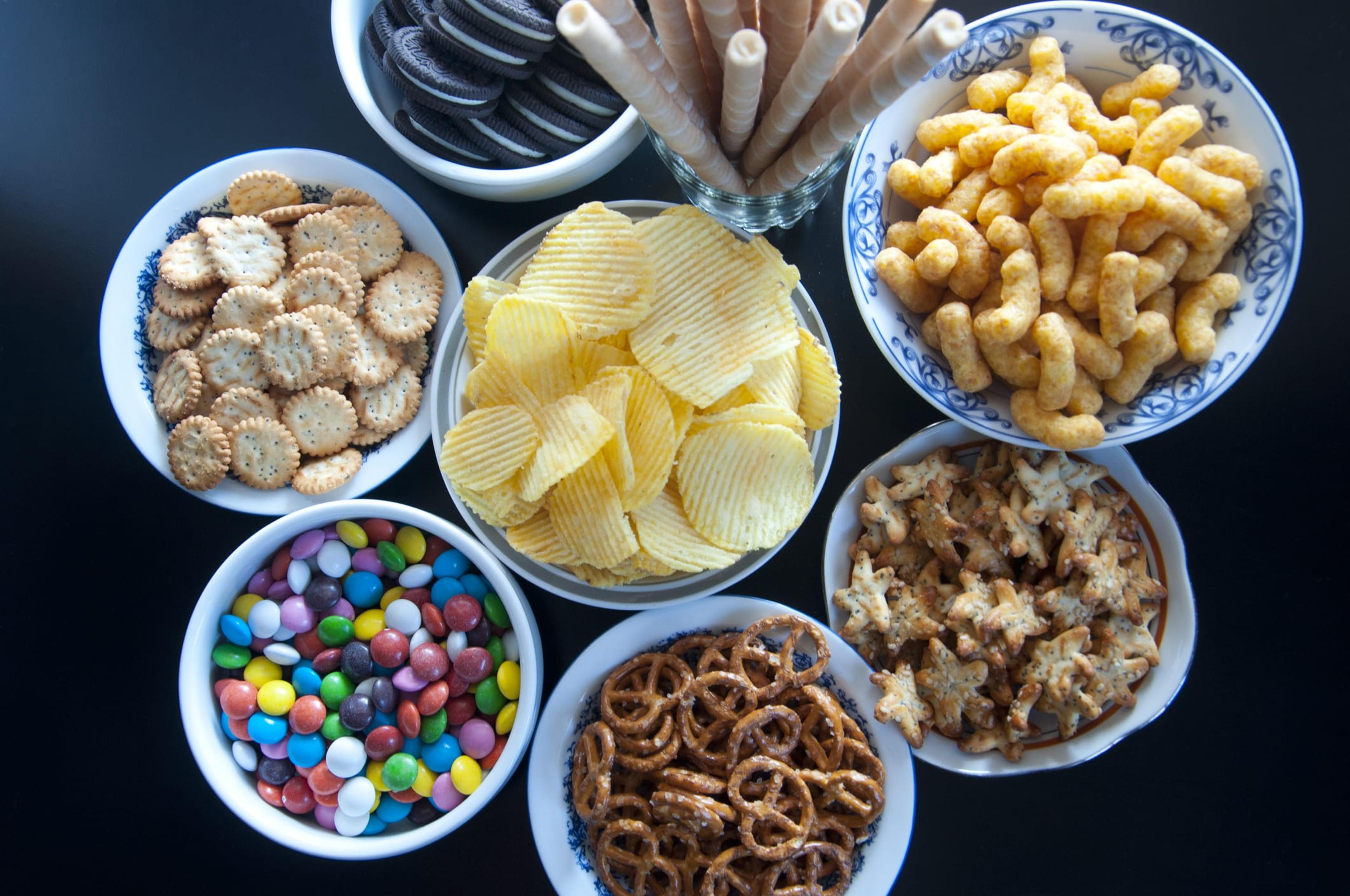 Table full of processed foods, potato chips, crackers, pretzels, cheese puffs, cookies