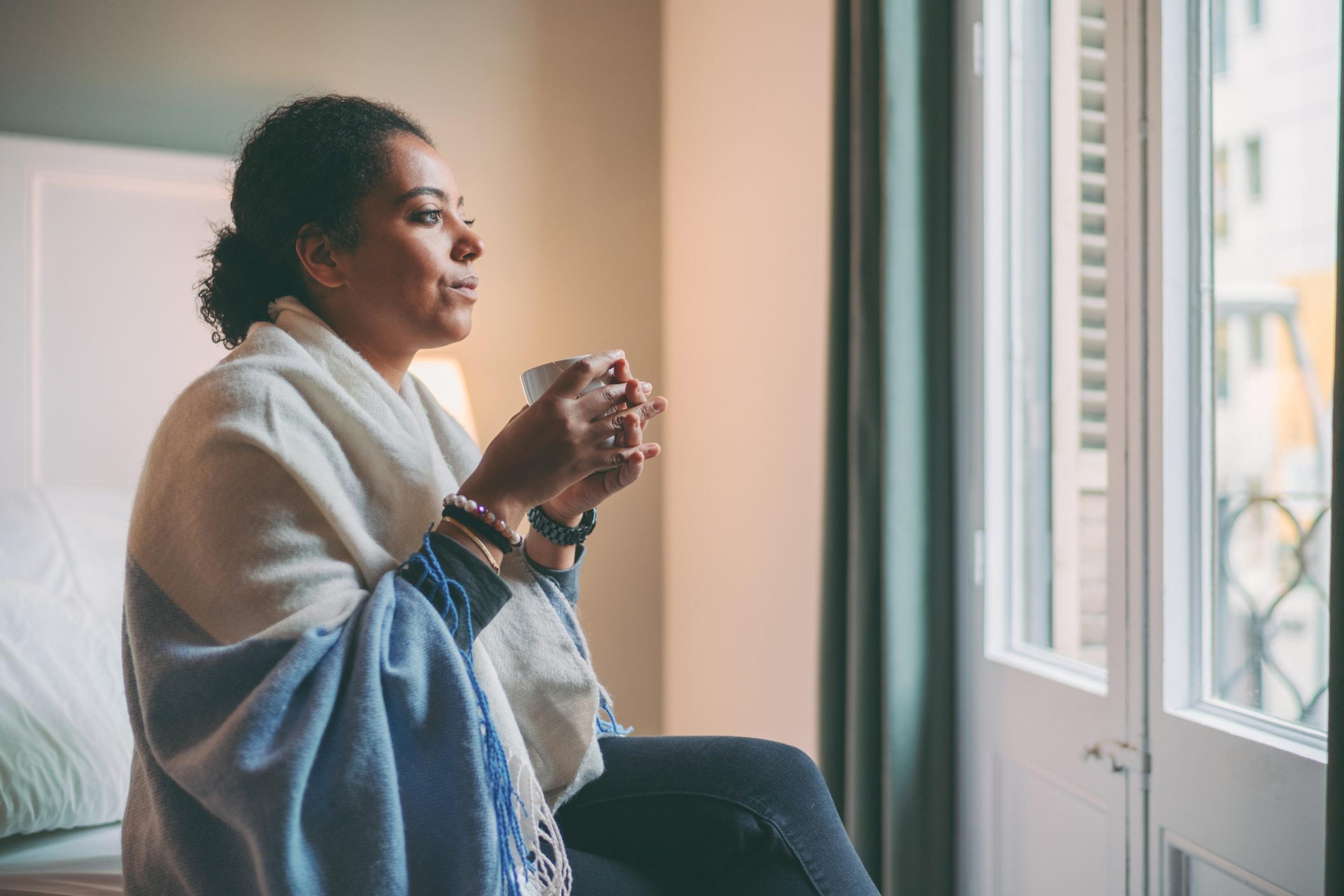 Woman holds a mug and looks out the window