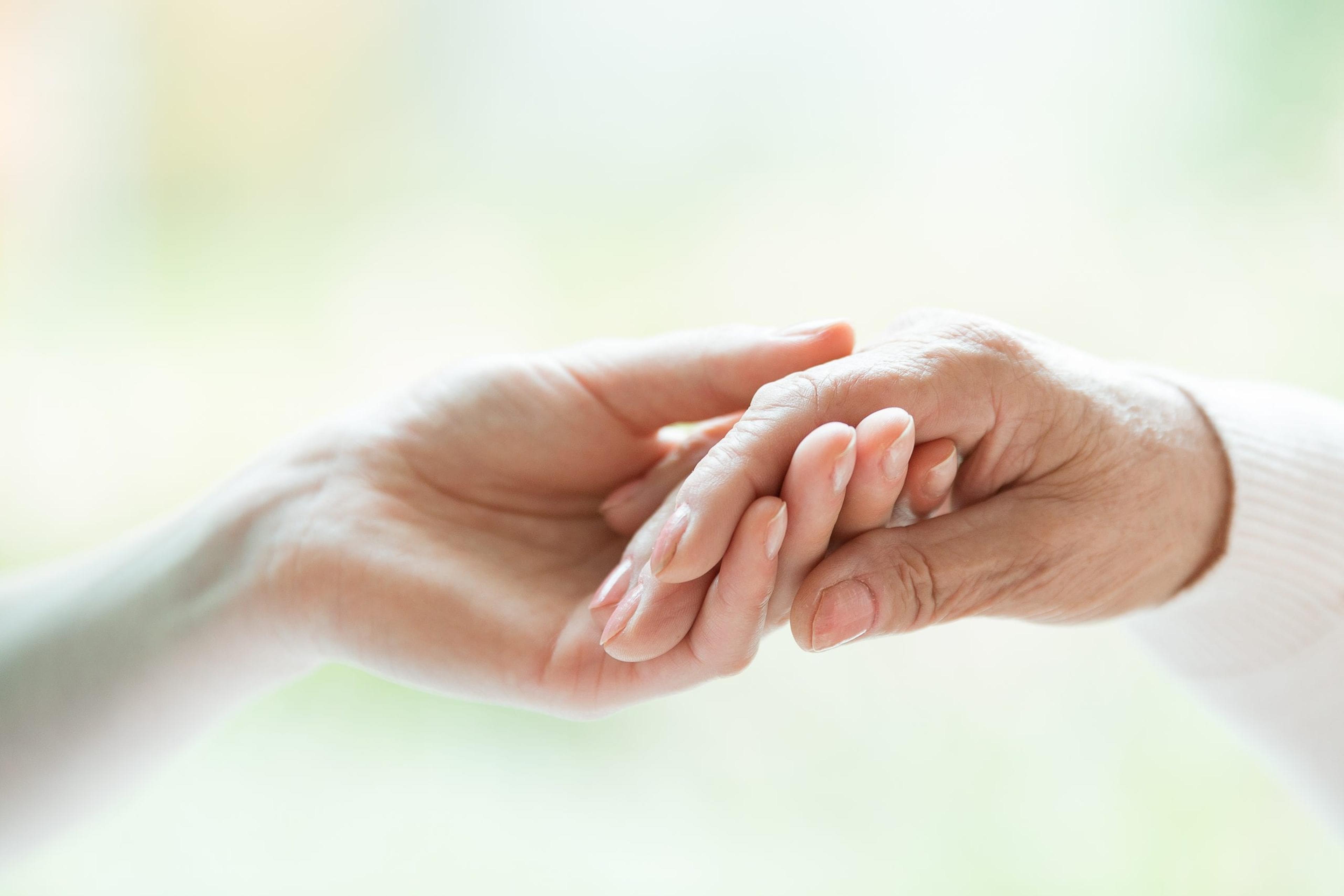 Photo of a young hand holding an older hand.