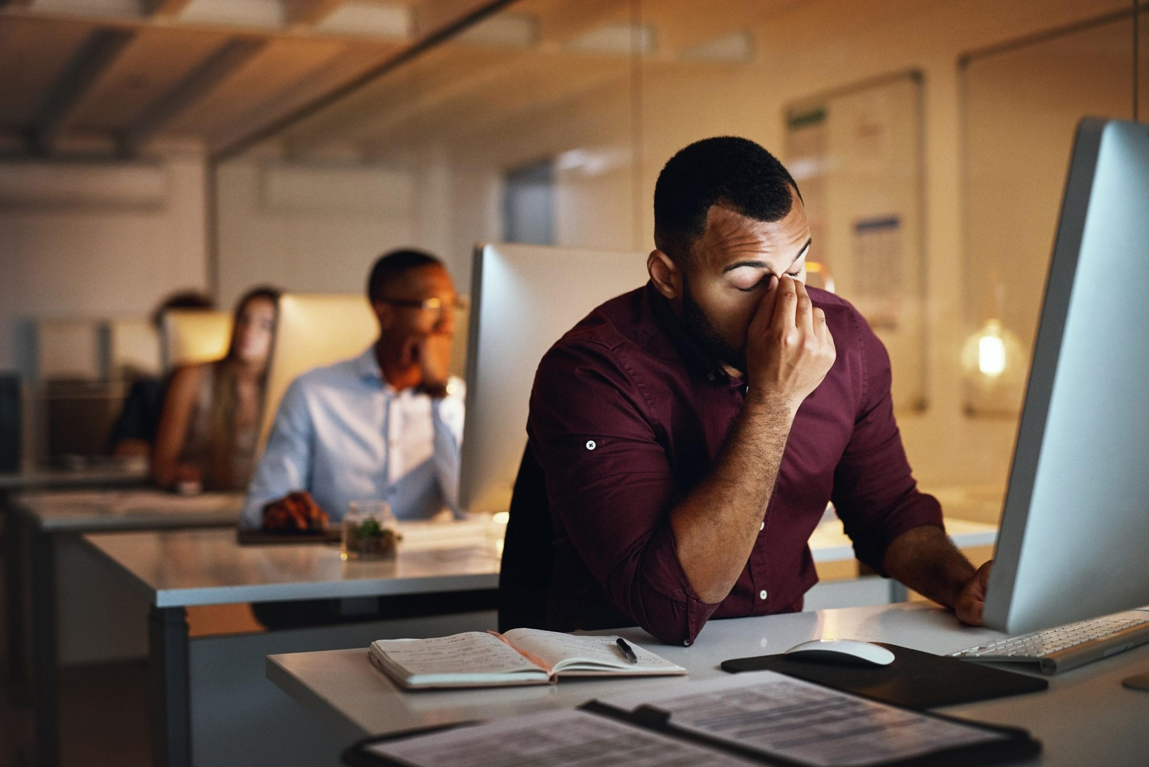 Shot of a young businessman looking stressed out while working late in an office