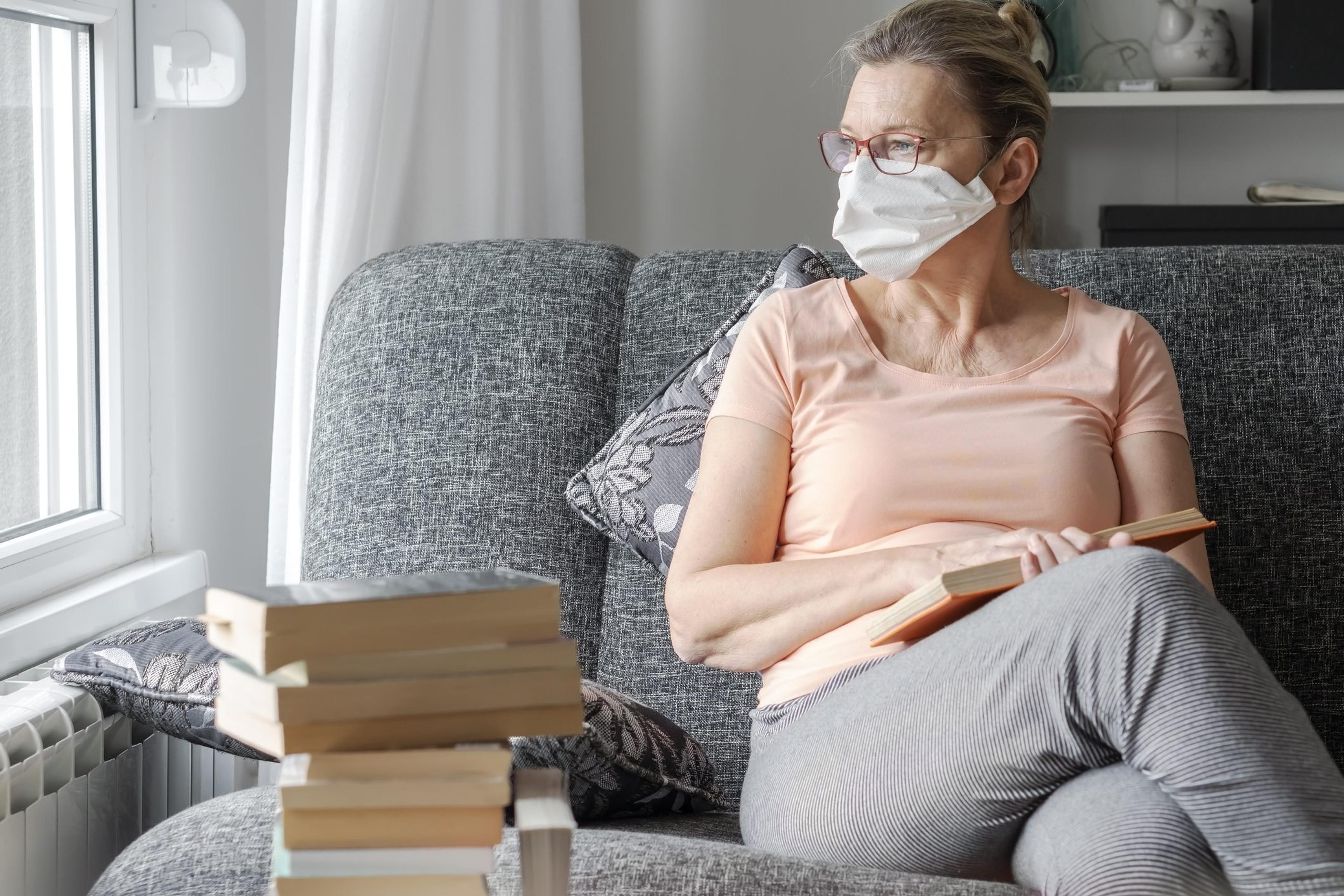 Woman in a mask looks out the window
