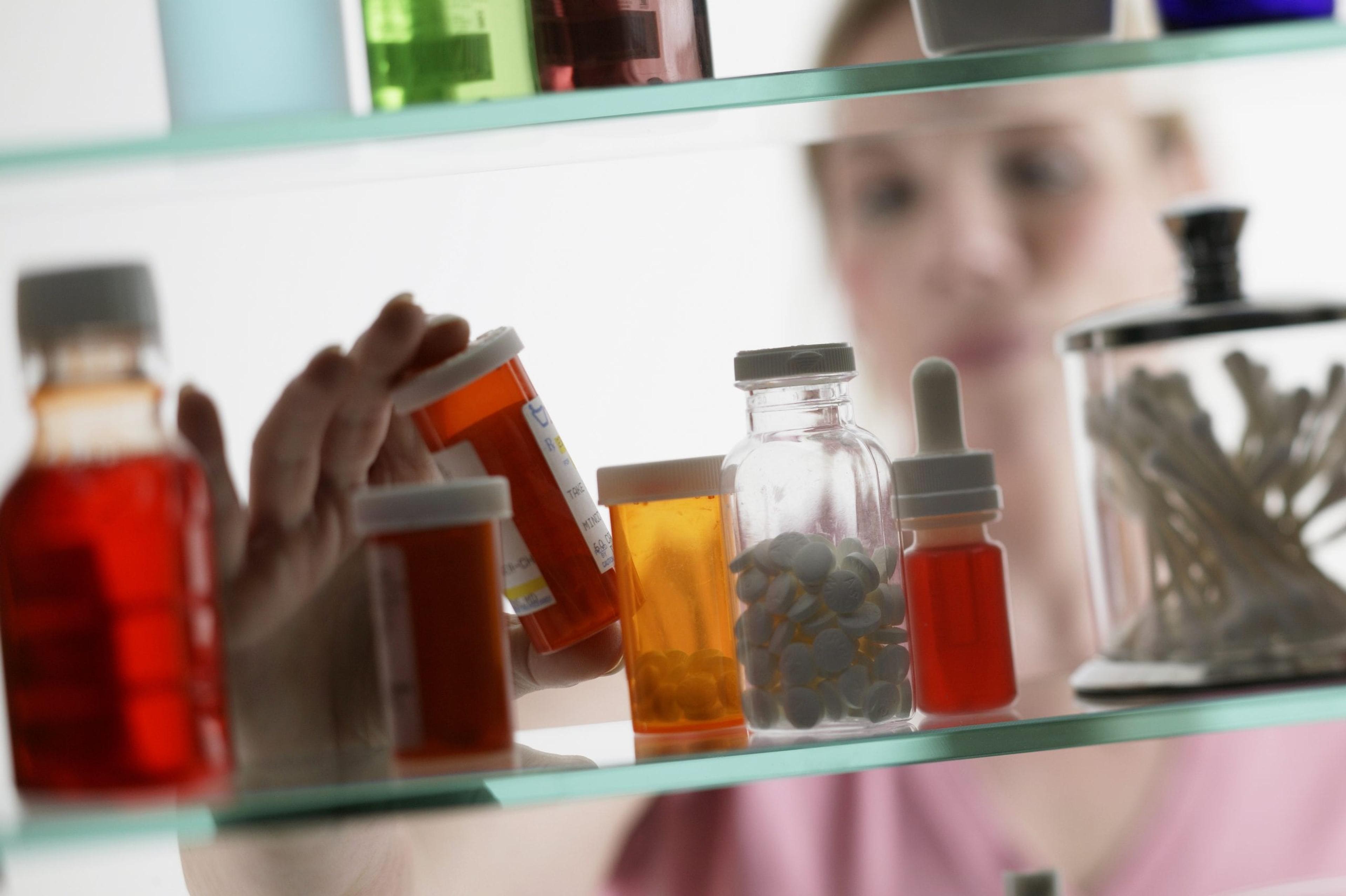 Woman reaching in medicine cabinet