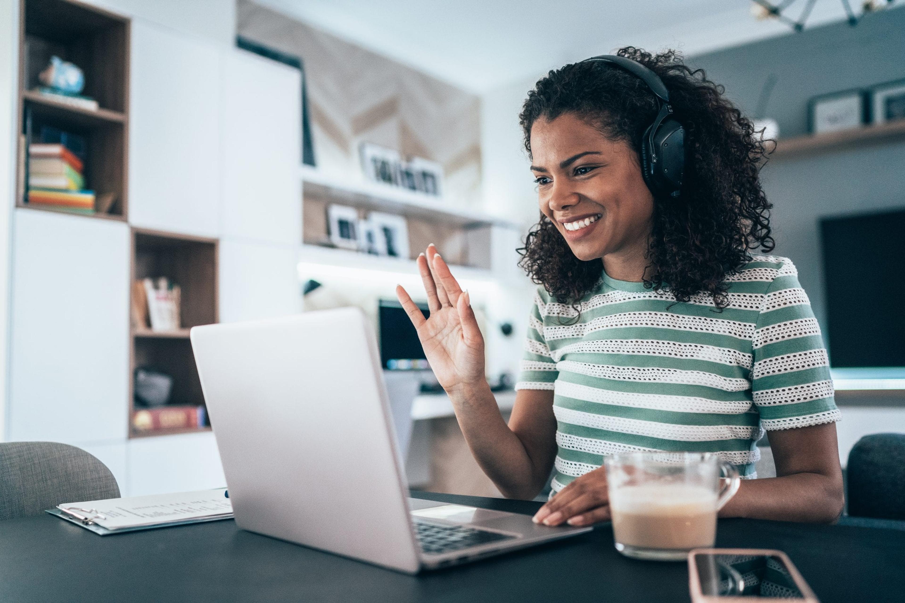 Woman waving to laptop screen