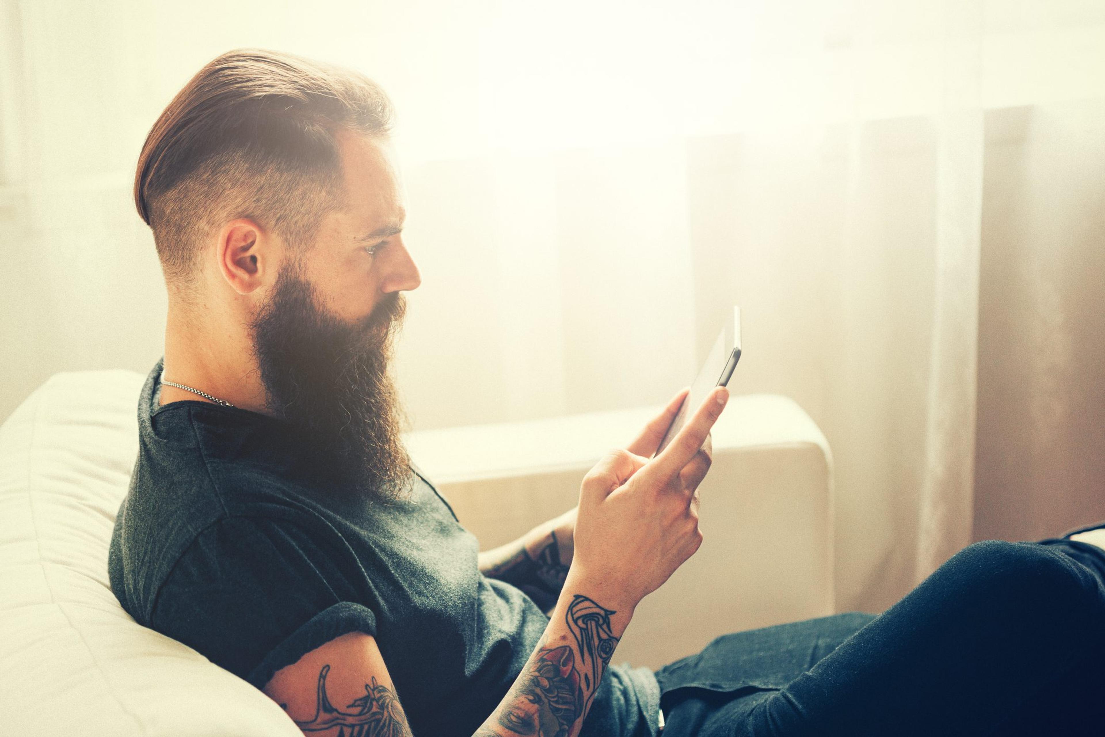 Young man with beard playing Tetris on his tablet at home