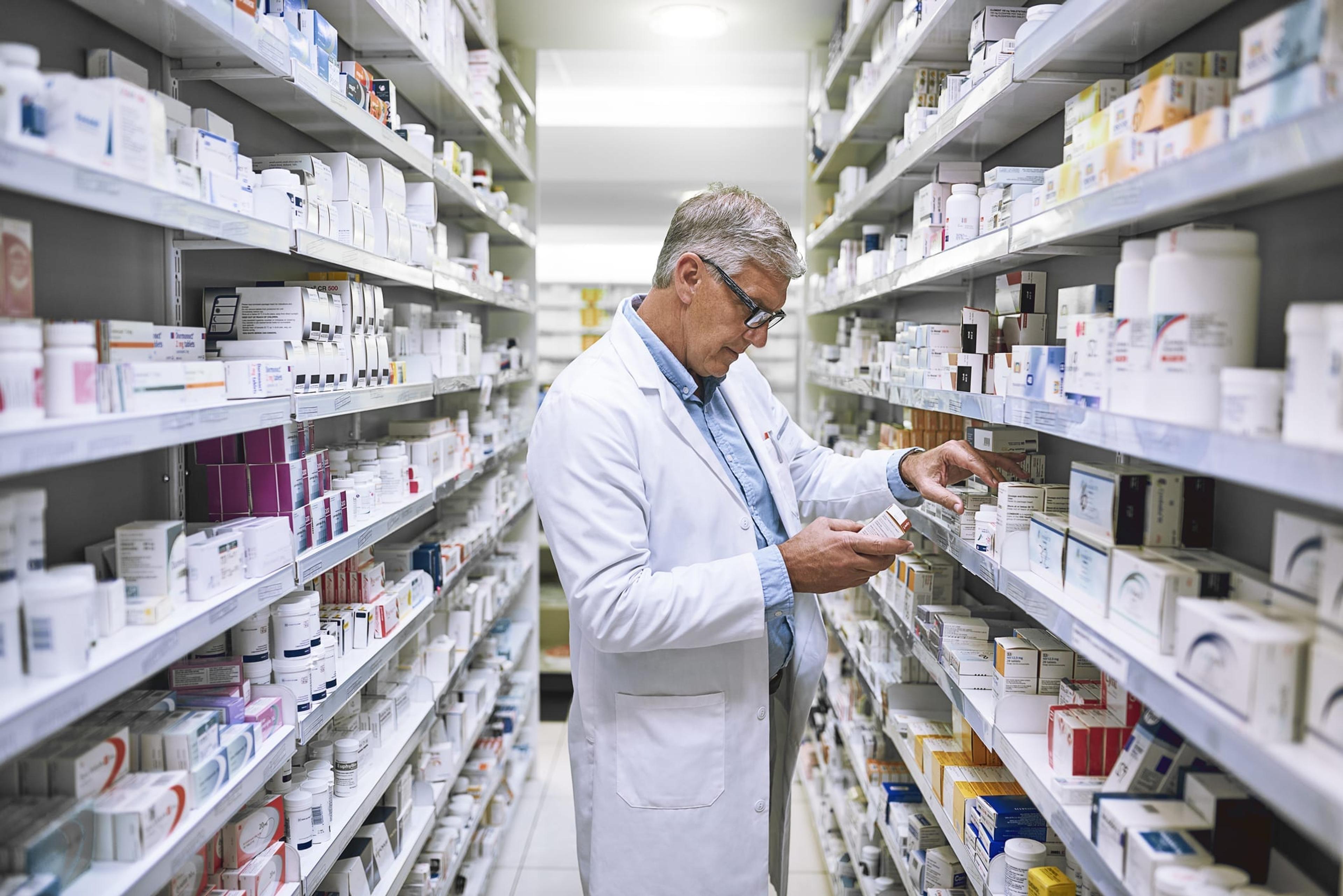 Male pharmacist makes notes on medication stock in a pharmacy