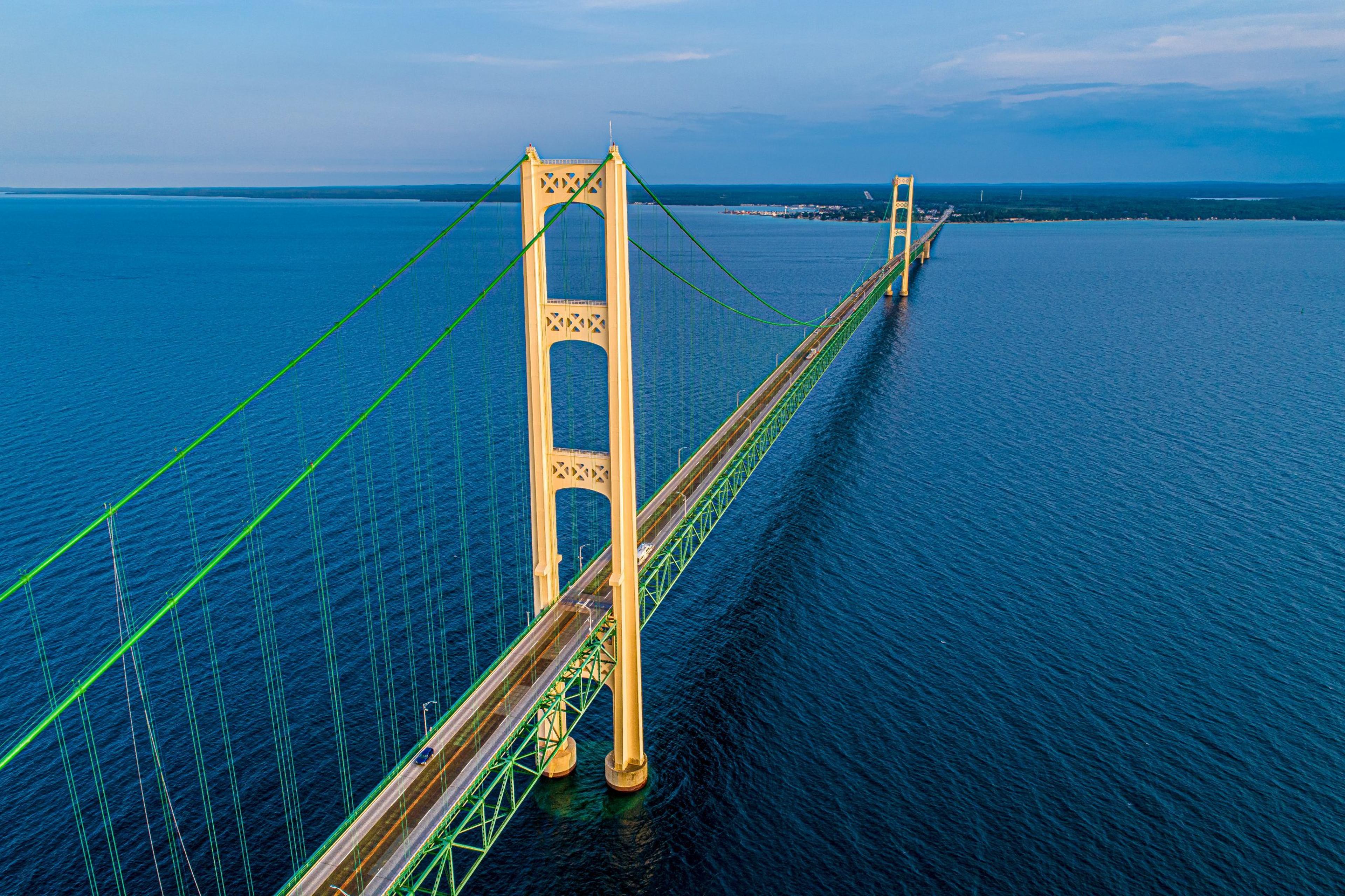 The Mackinac Bridge stands tall over the deep blue waters of the lake on a sunny day.