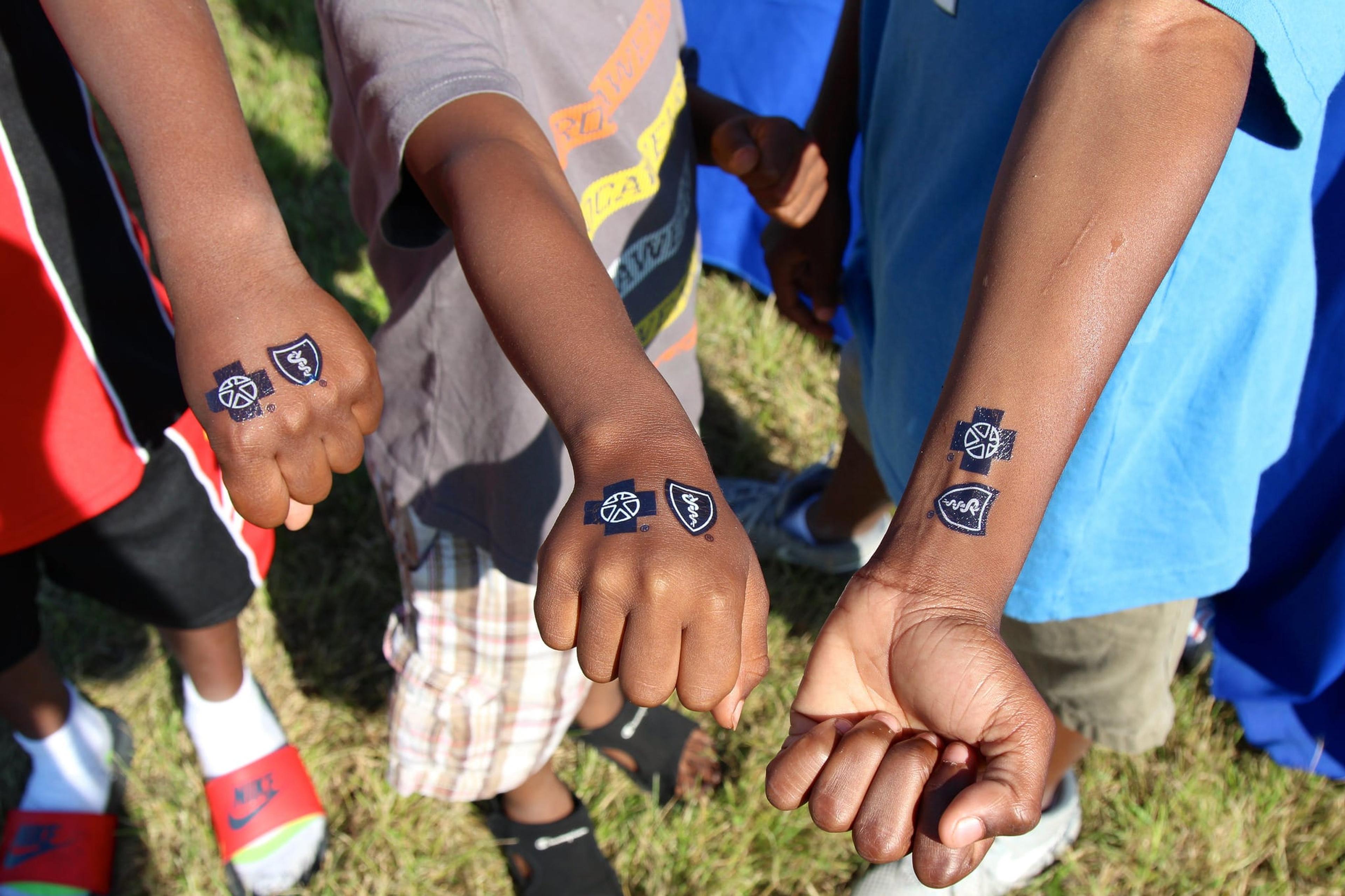 Photo depicts three young people's hands and arms with Blue Cross Blue Shield of Michigan temporary tattoos displayed.