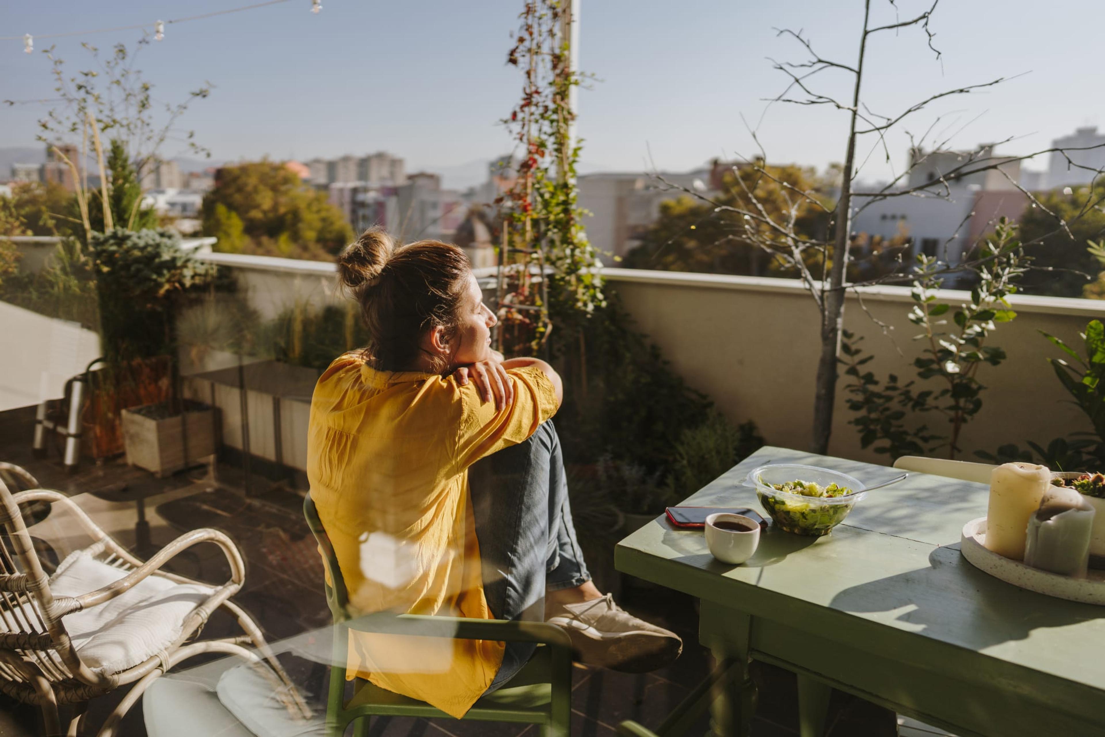 Woman sits on a chair on a balcony in the sun