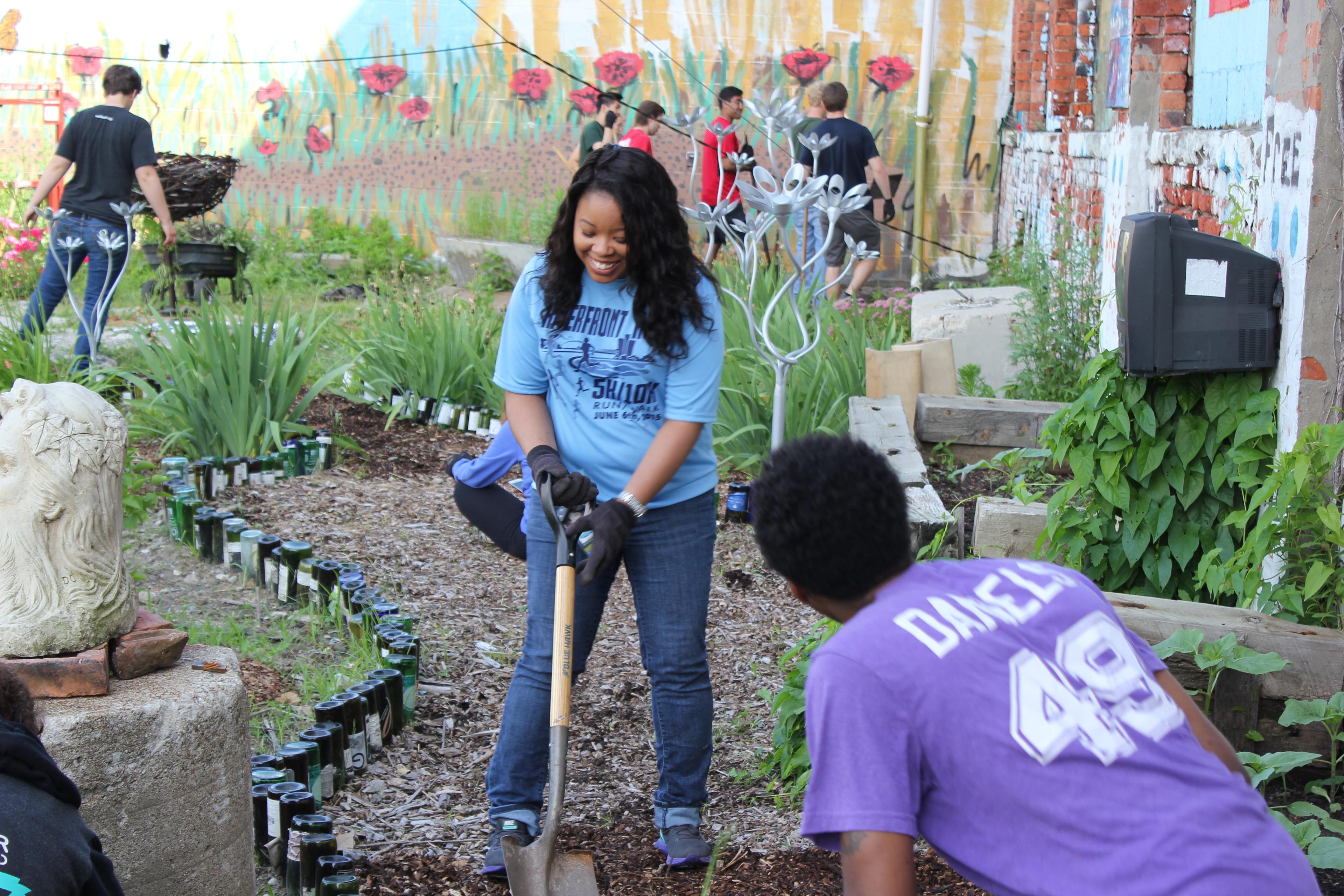 Girl holding shovel digging a garden at volunteer project