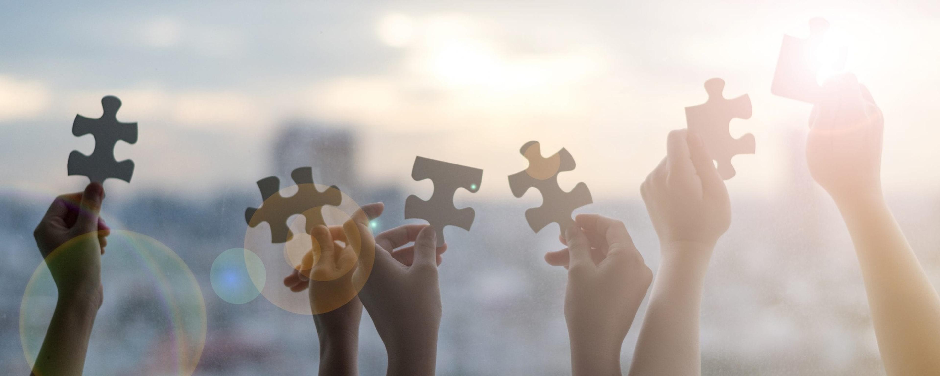 Children's hands holding up puzzle pieces to the light