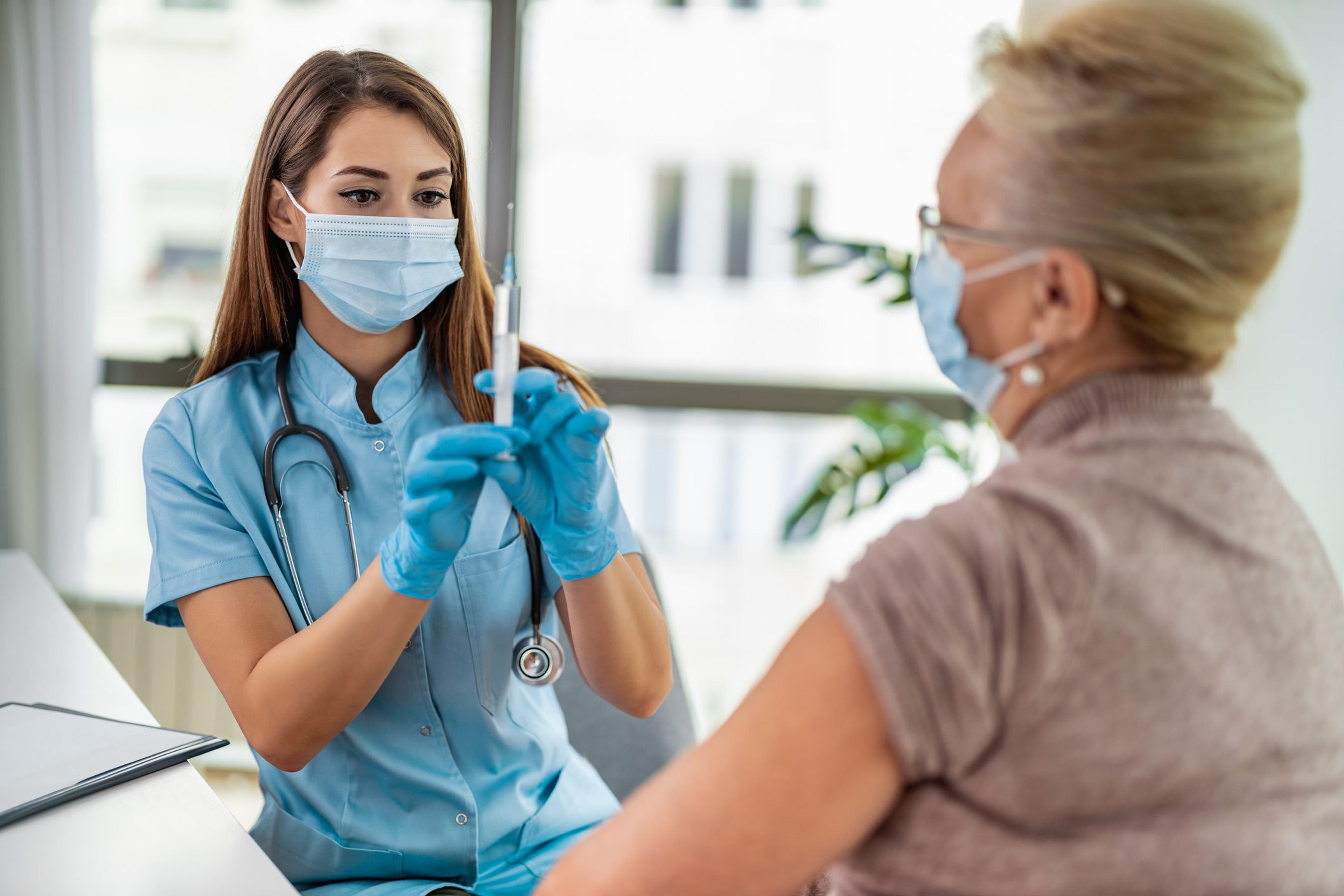 Female doctor giving a consultation to a senior patient on a second COVID-19 vaccine booster shot