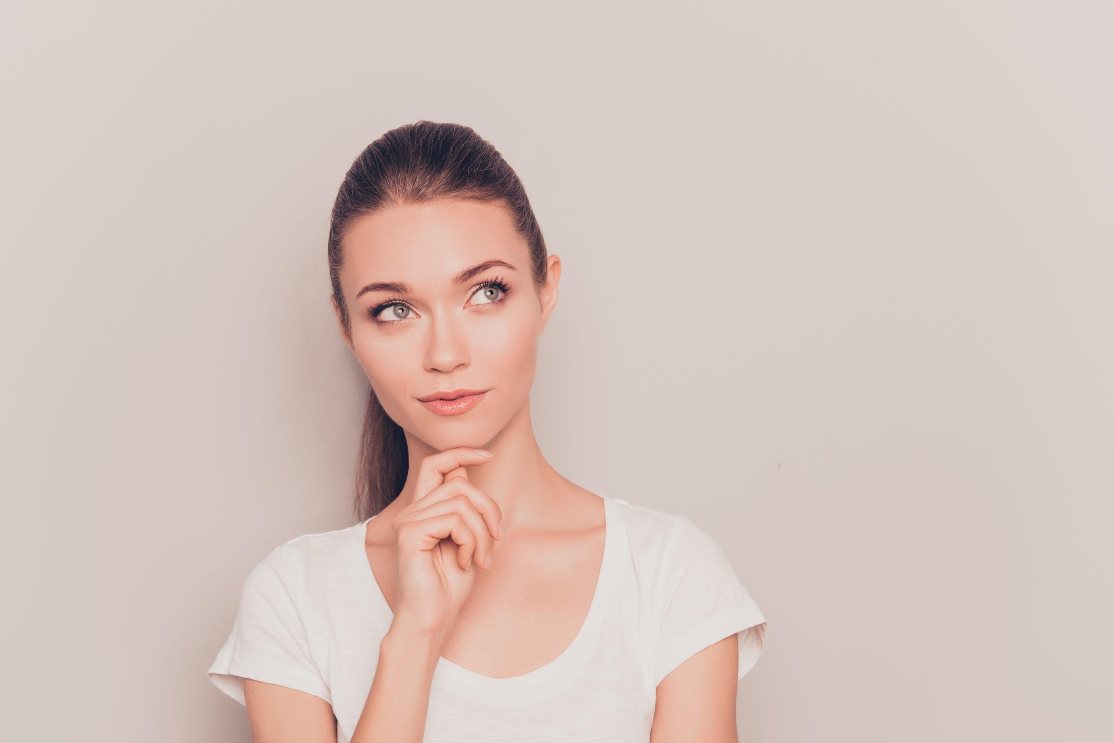 Young woman dreaming in front of a gray background