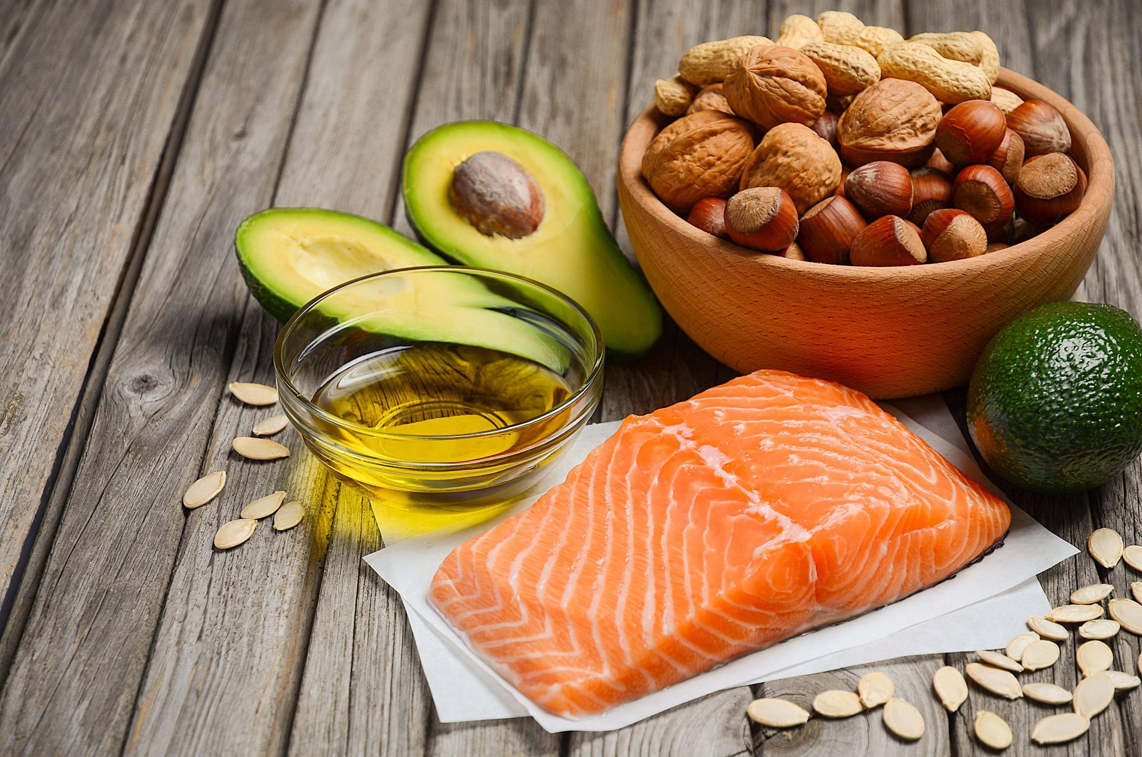 Selection of healthy fat sources salmon, cashews, olive oil. avocado