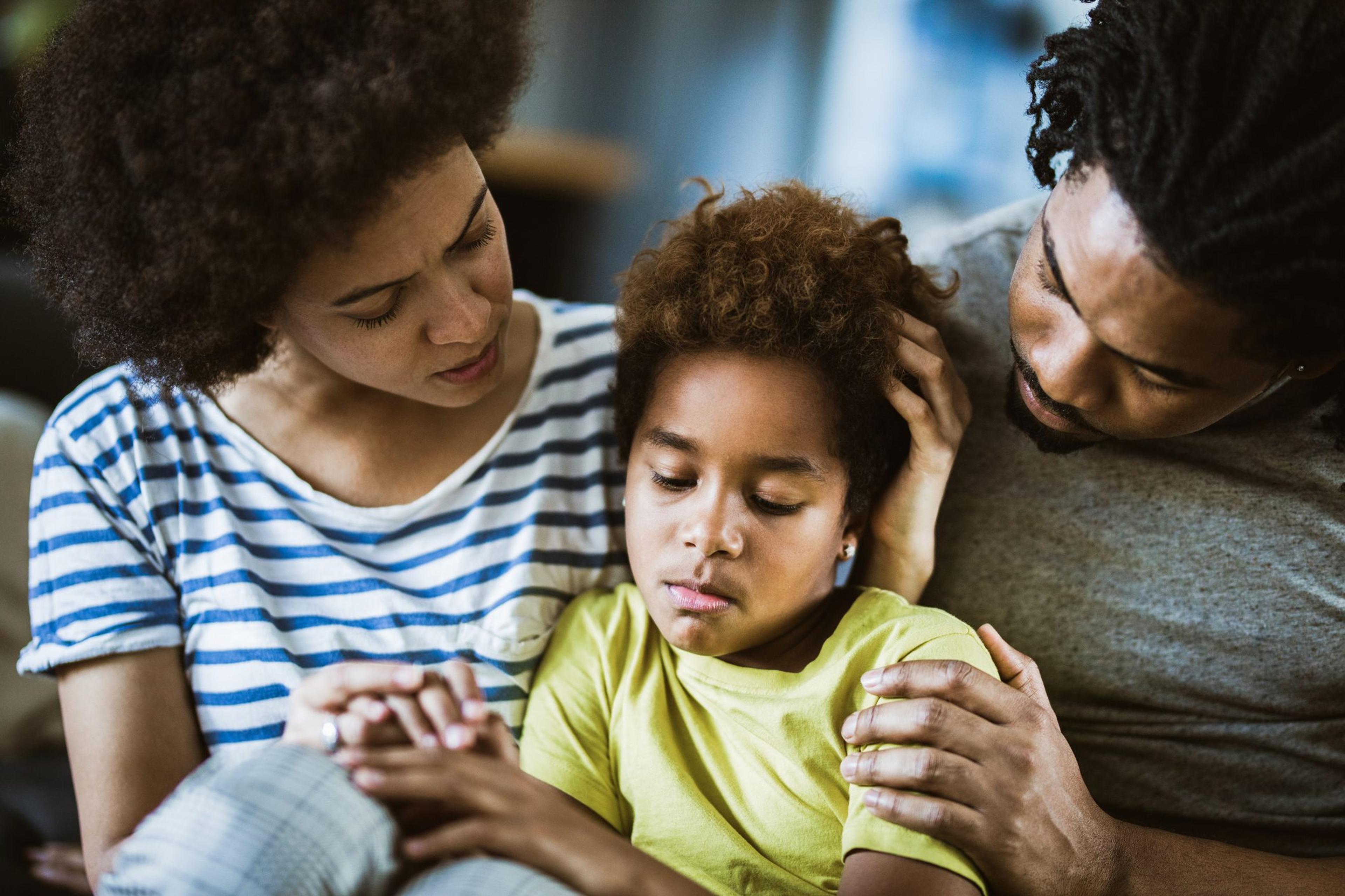 African American parents consoling their sad girl at home.