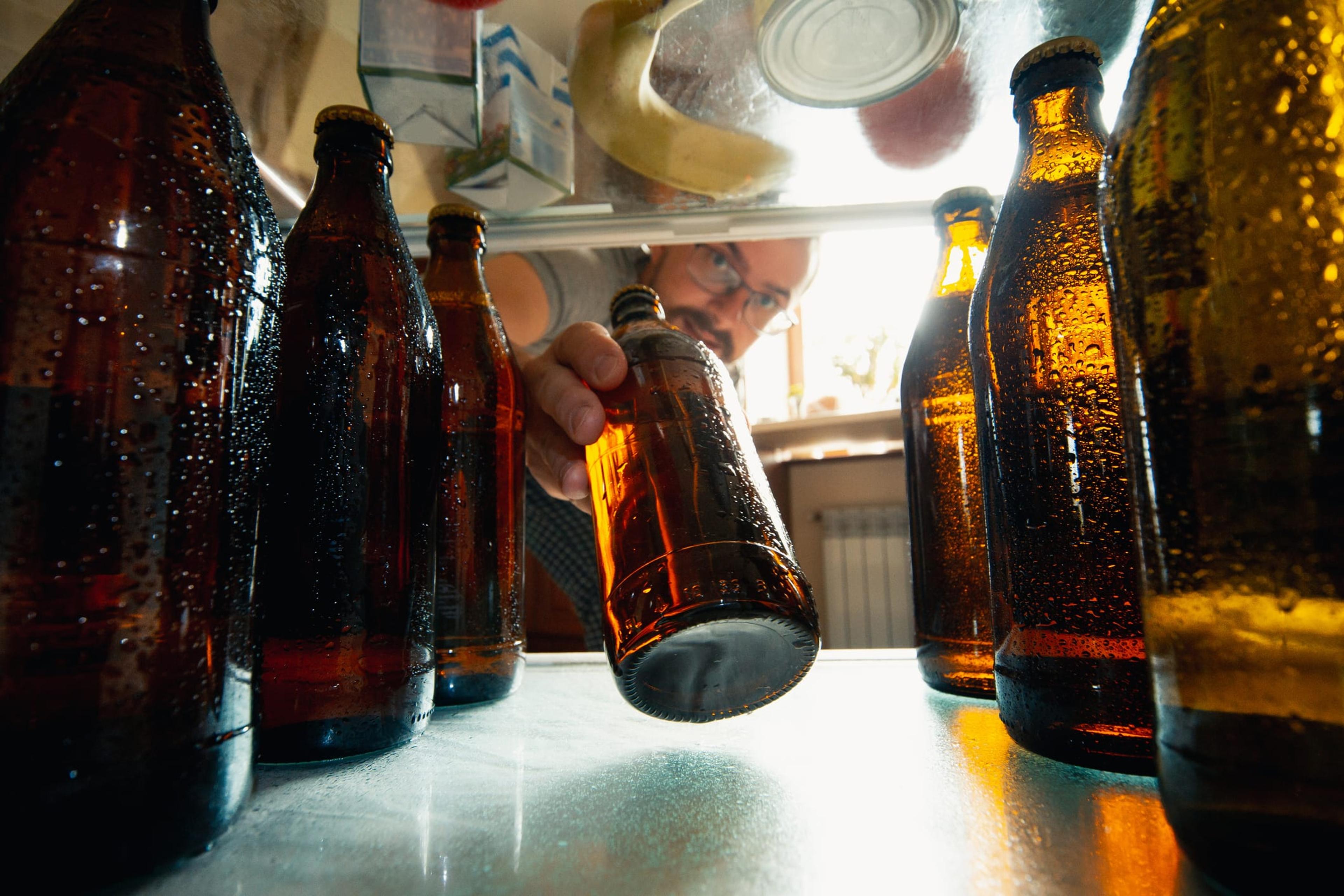 Man takes a beer bottle out of the fridge binge drinking