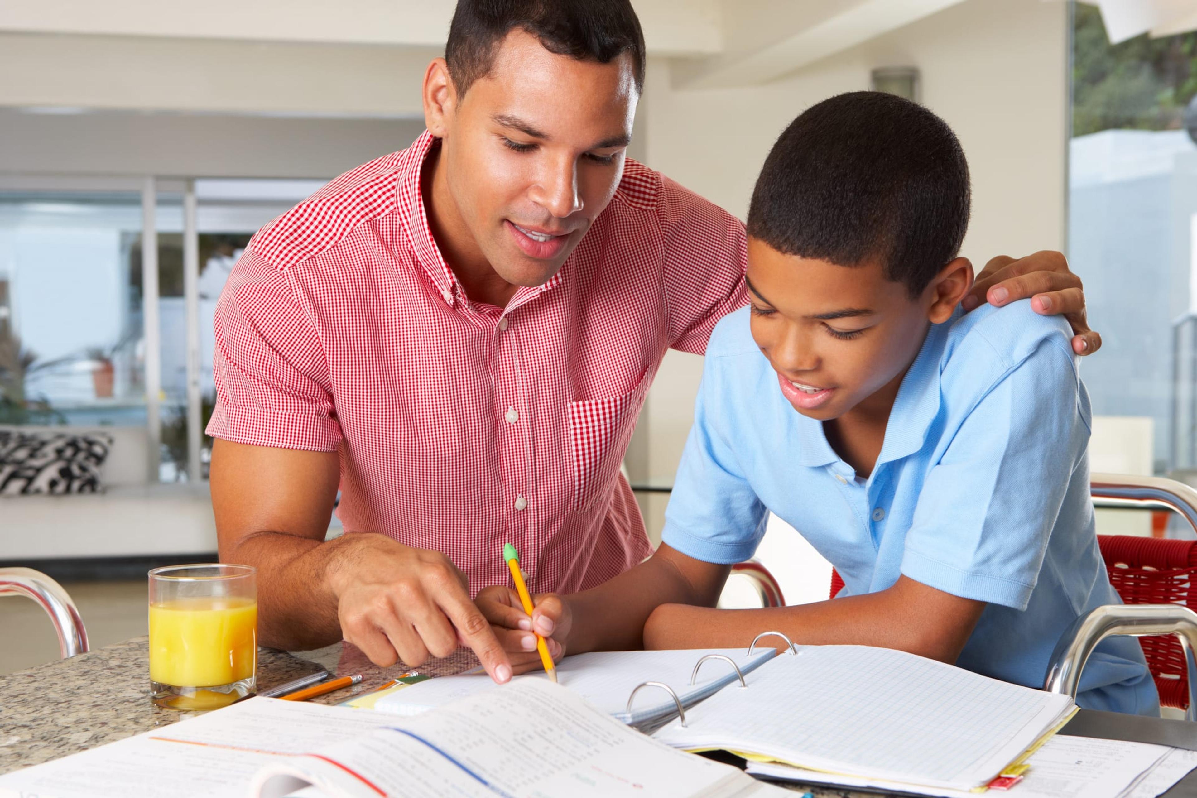 Father helps his son in the kitchen with homework