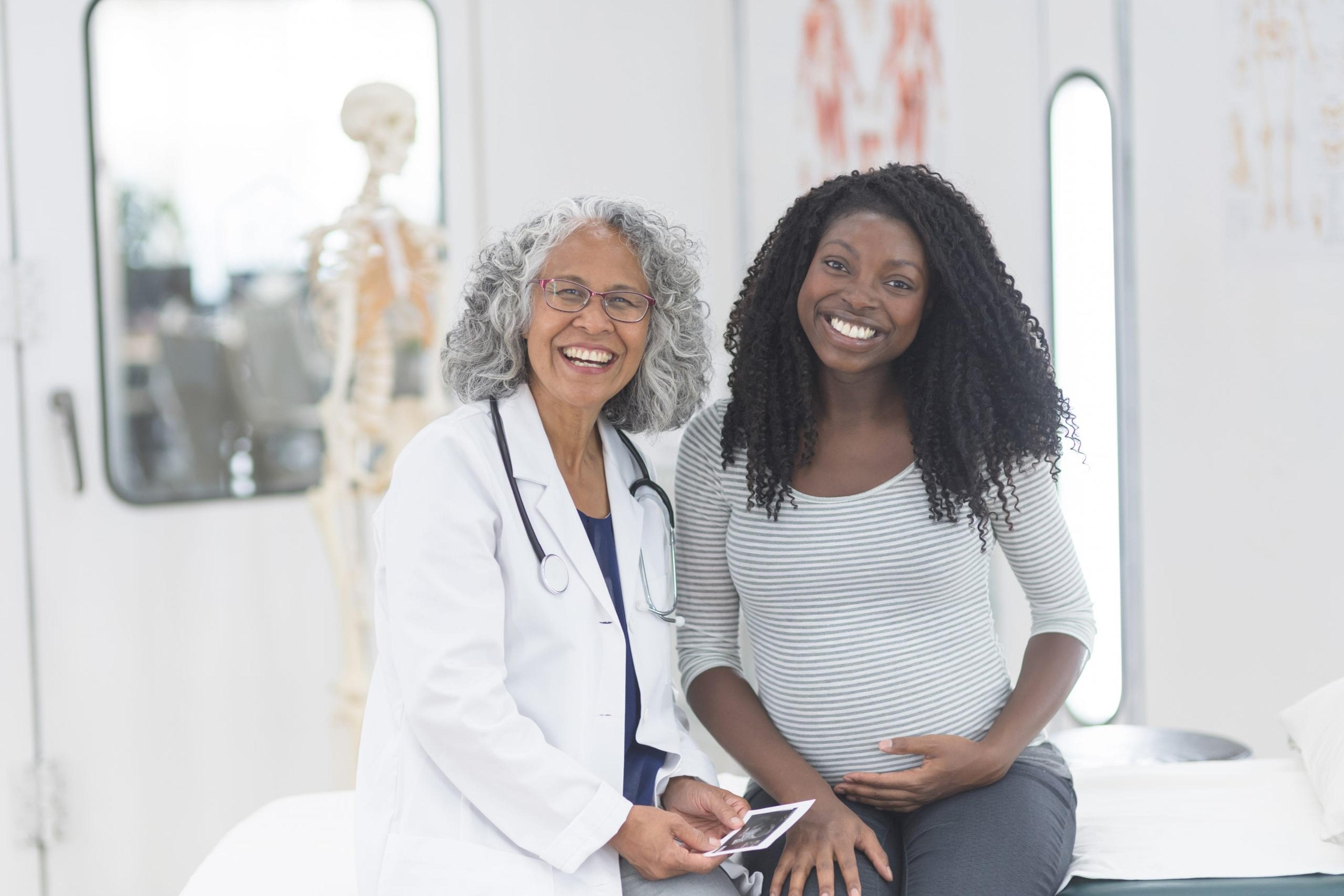 Pregnant woman smiling with her doctor.