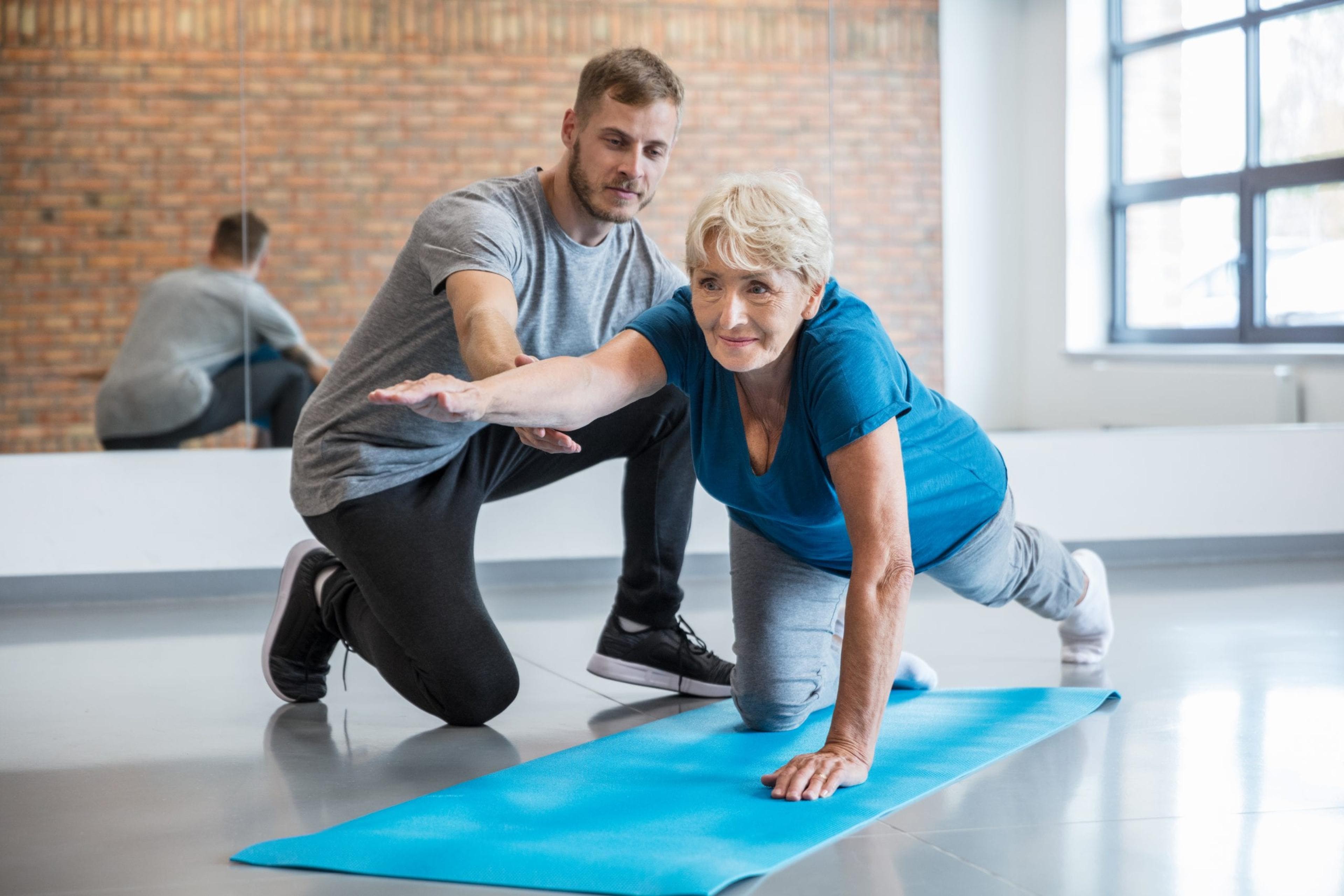 Senior woman being helped by her trainer.