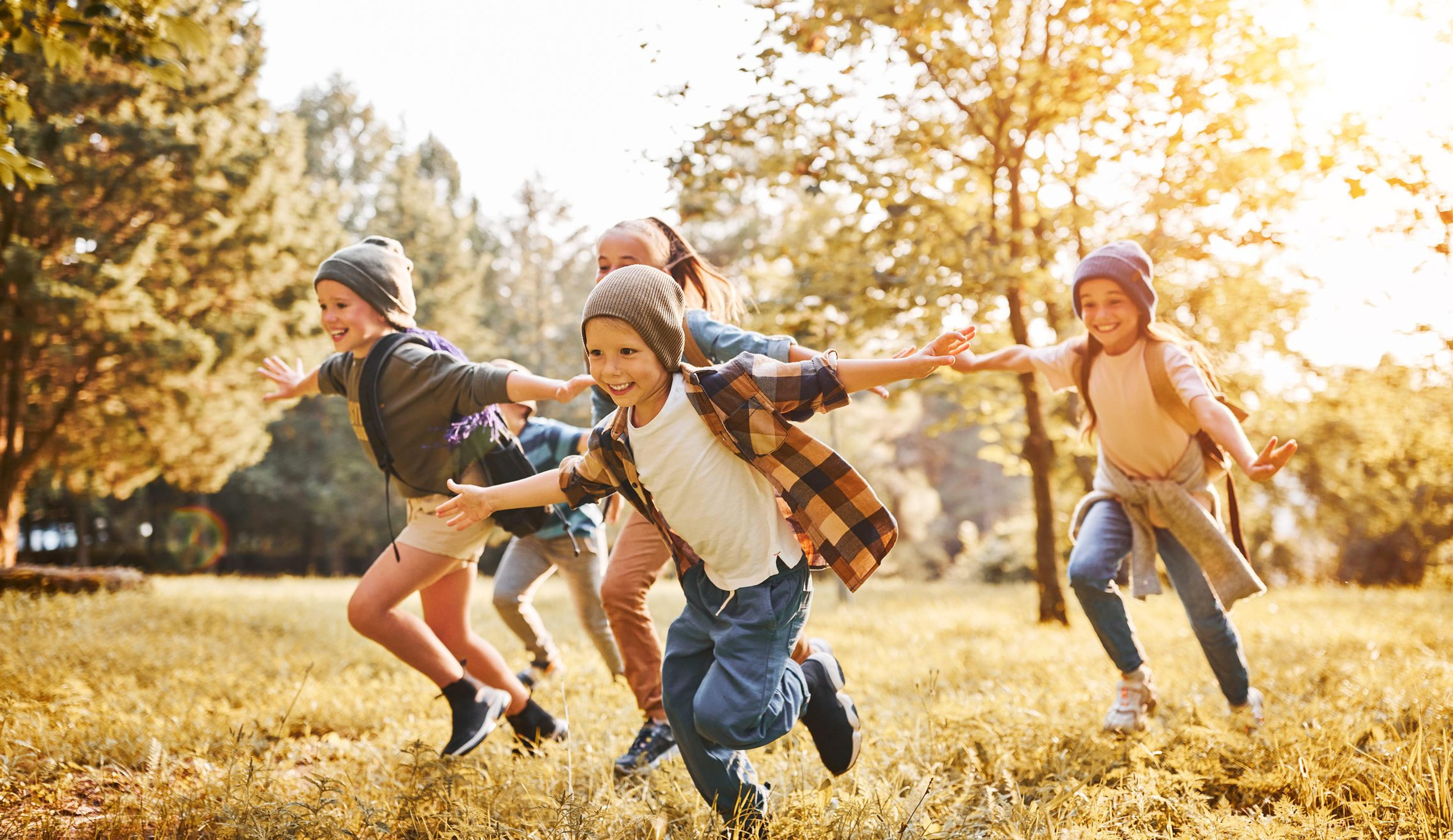 Group of happy joyful school kids boys and girls running with ou