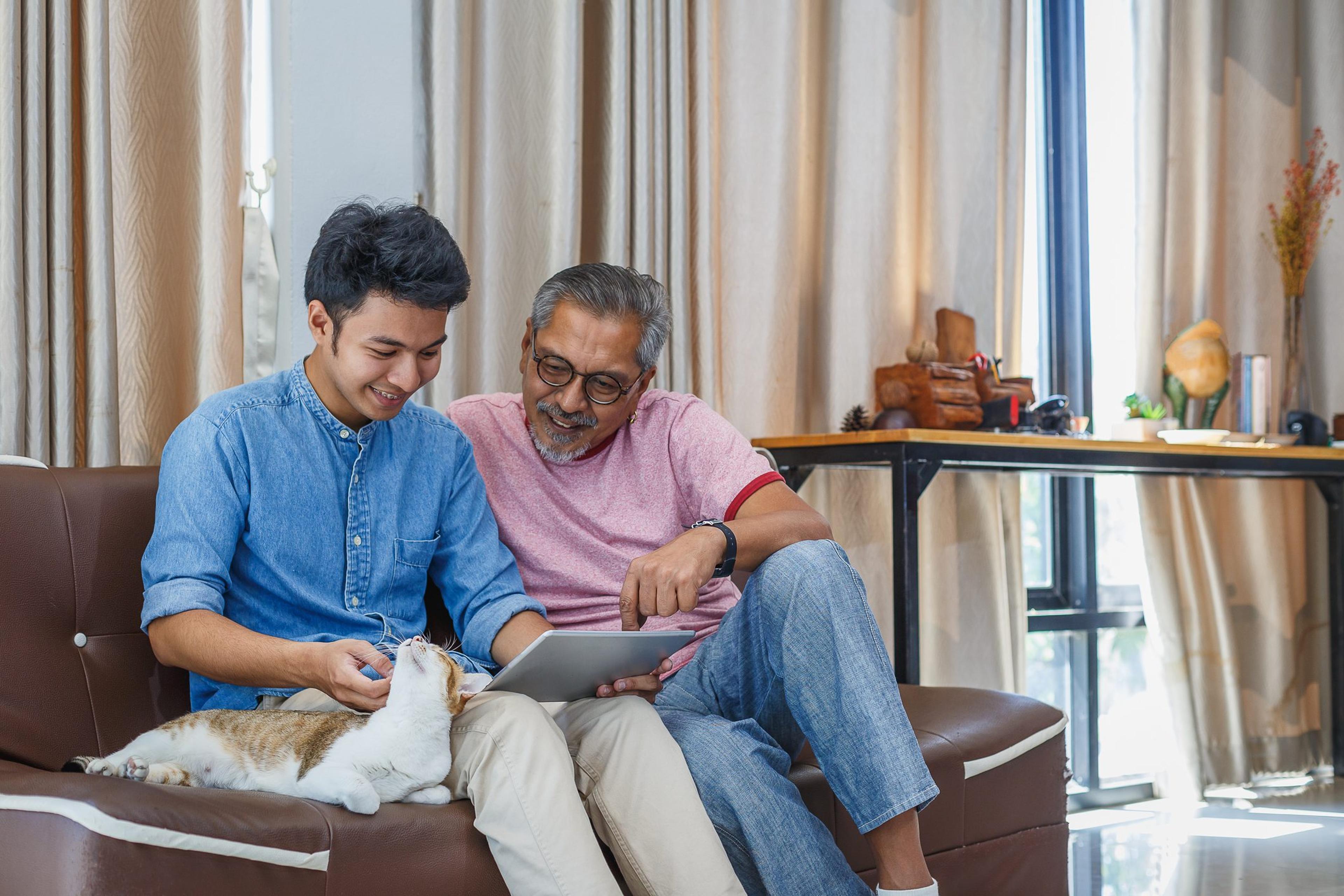 Father and teen son look at a tablet together