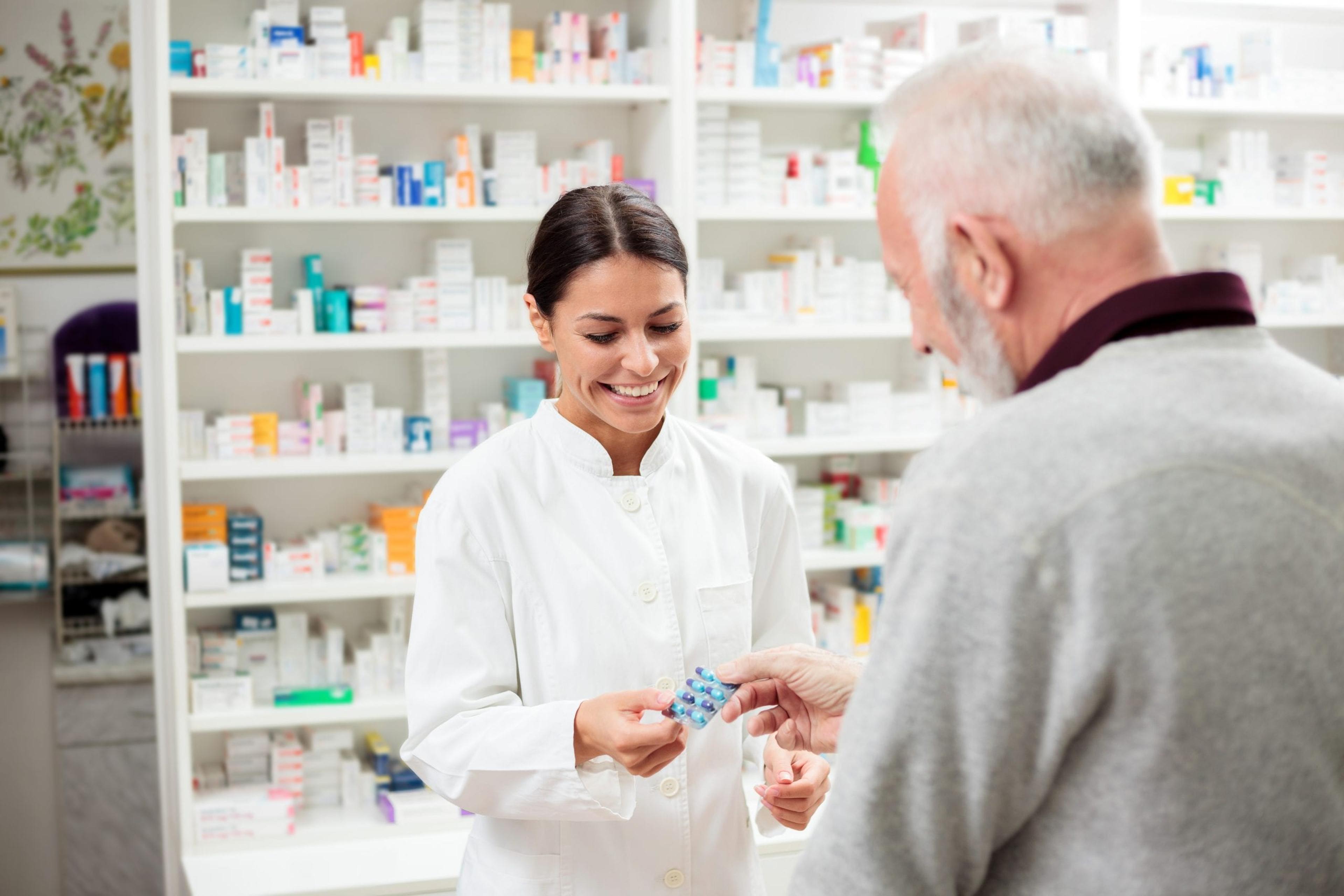 Female pharmacist giving medication to a customer.