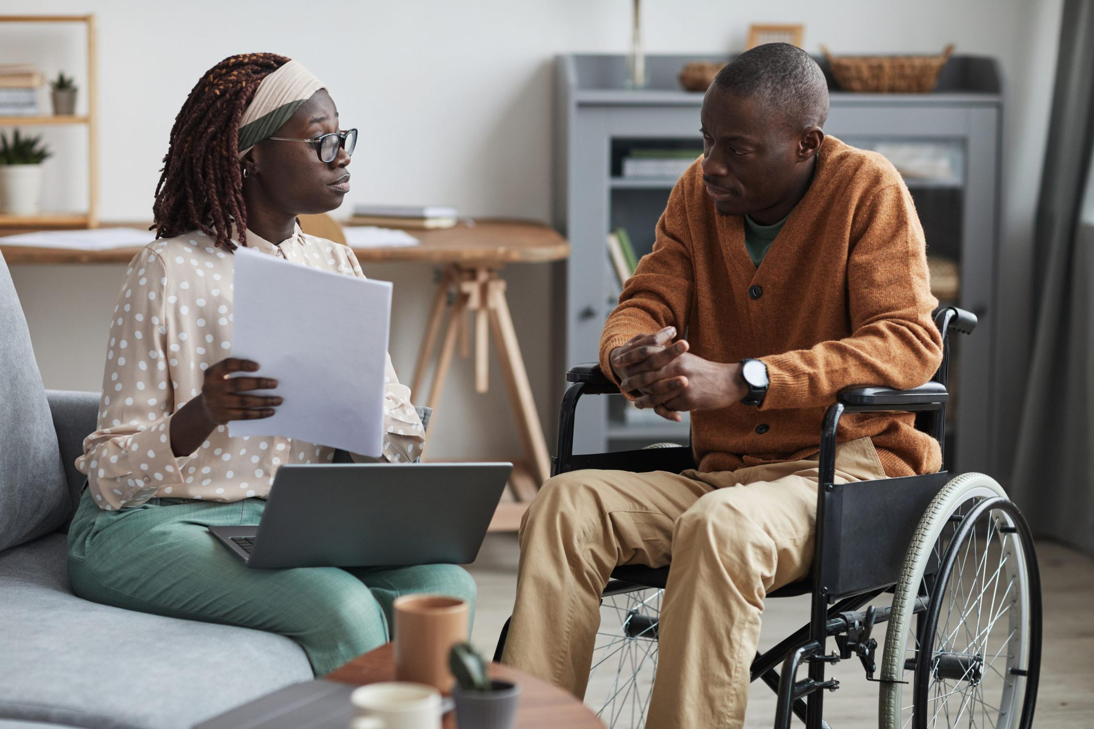 Female case worker meeting with a man sitting in a wheelchair