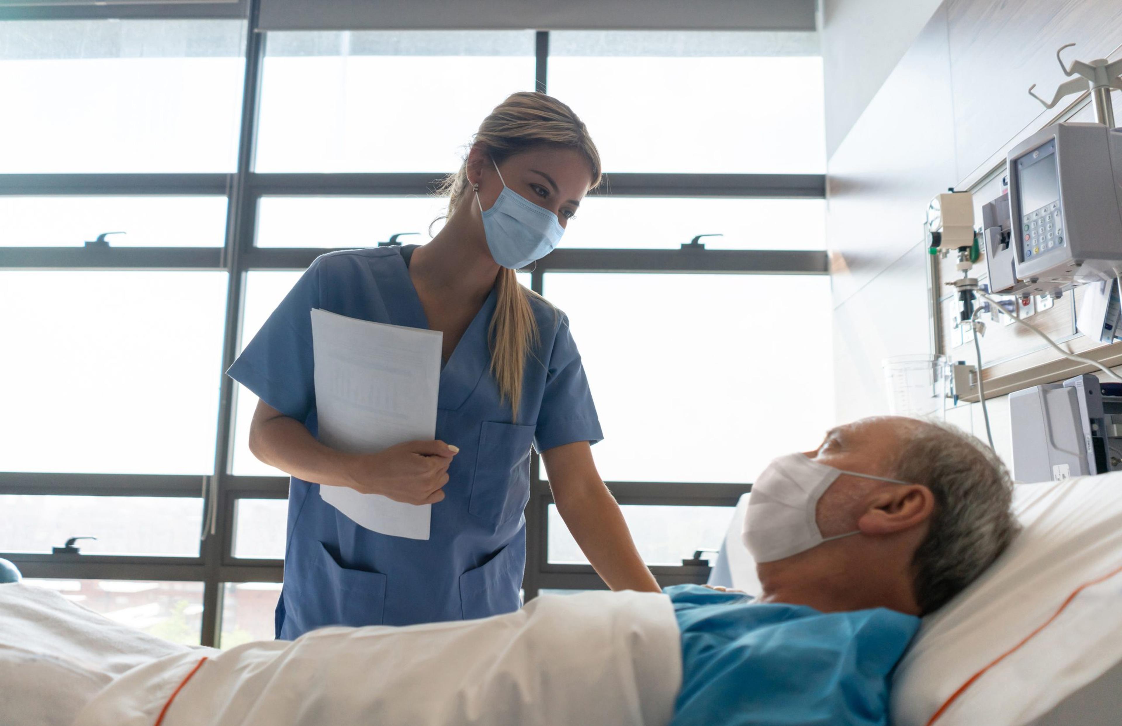 Nurse wearing a facemask while checking on a patient at the hospital