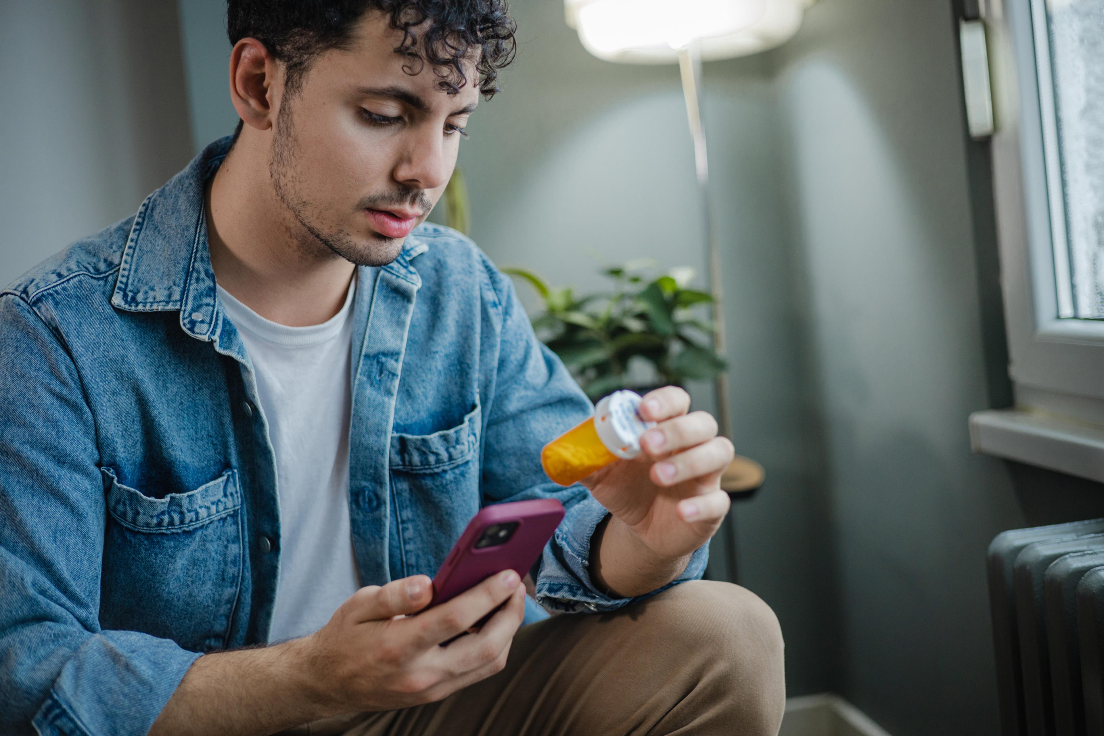 Young man looks at a prescription drug label