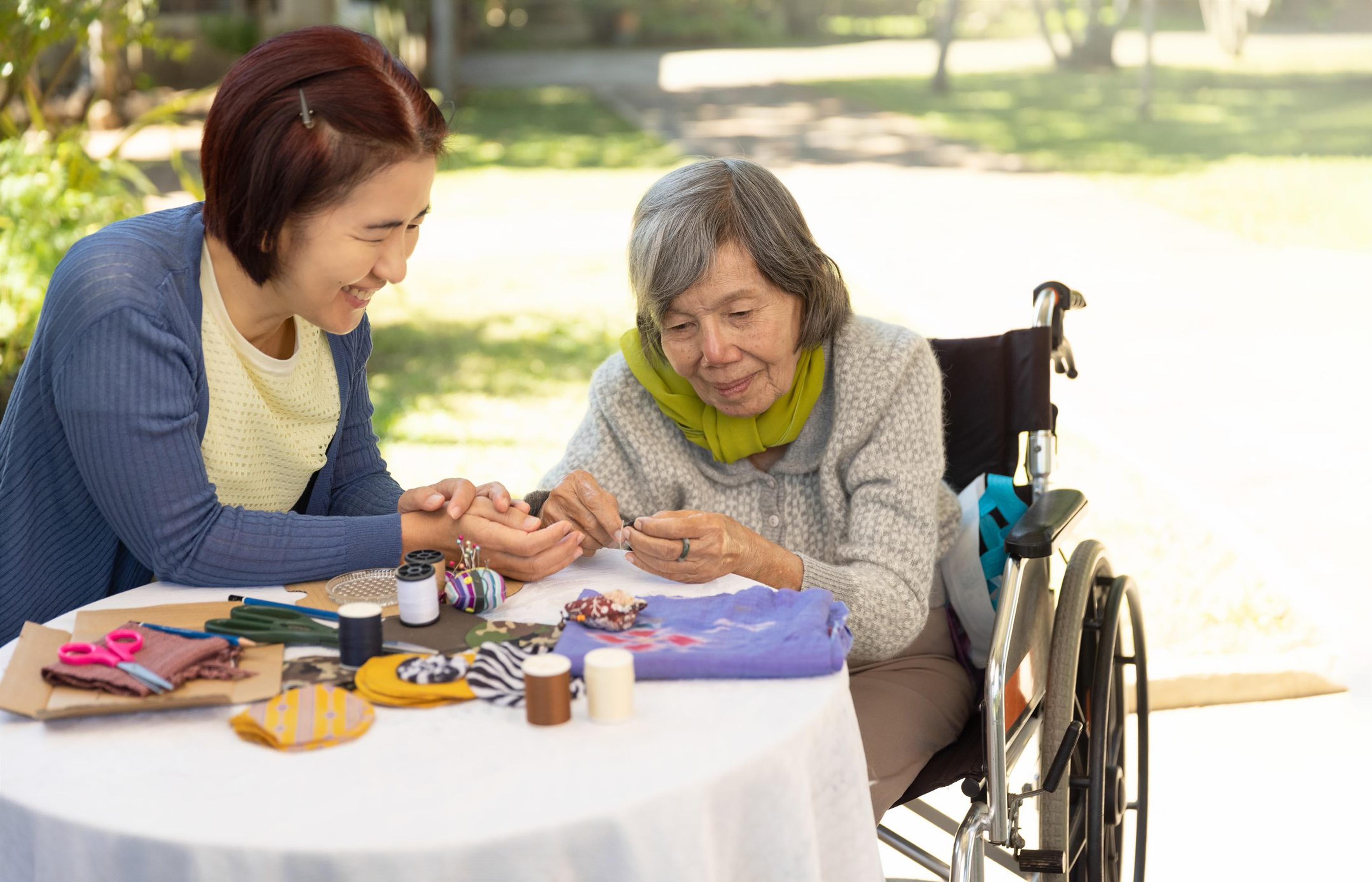 Elderly woman and daughter in the needle crafts occupational therapy for Alzheimer’s or dementia