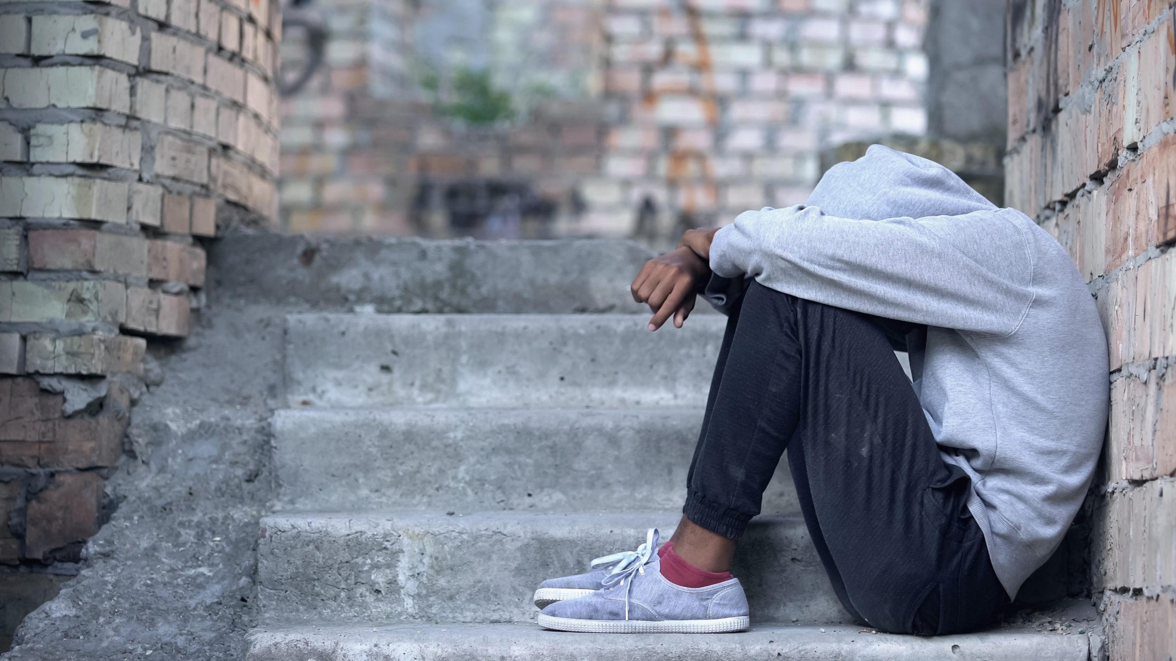 Teen sitting on stairs with head in hands