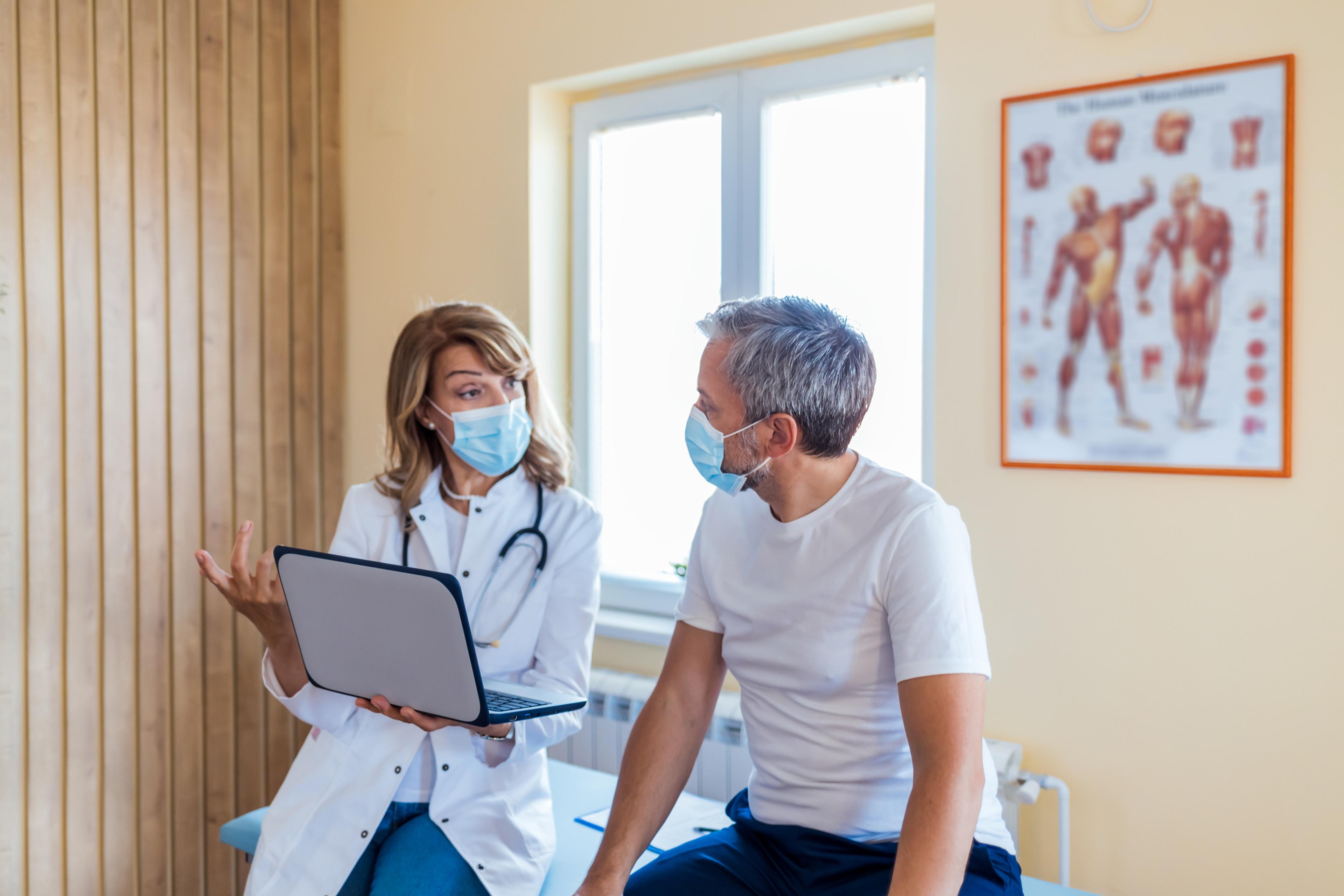 A man speaks with a female doctor during an appointment.