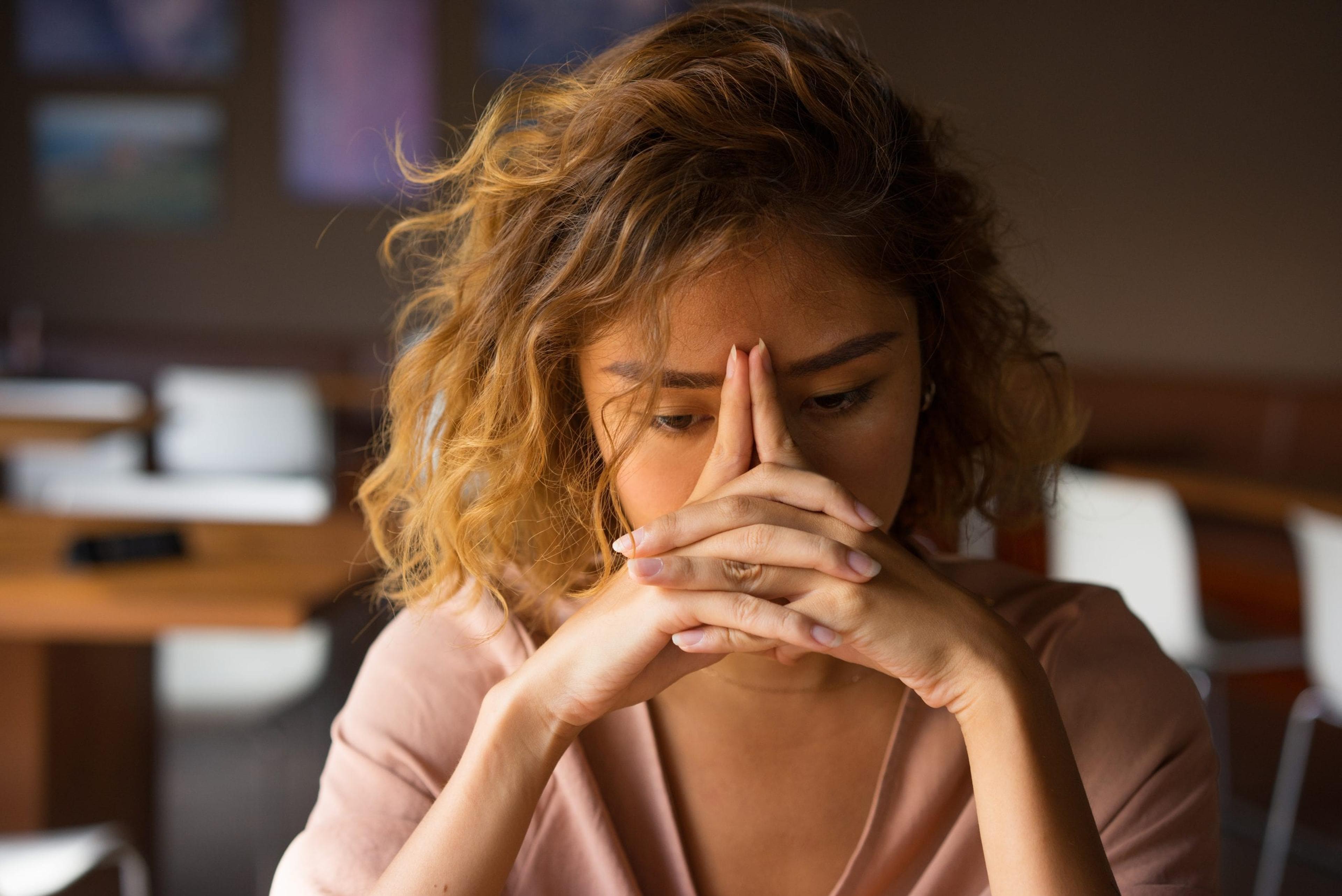 Stressed woman with hands in front of face.