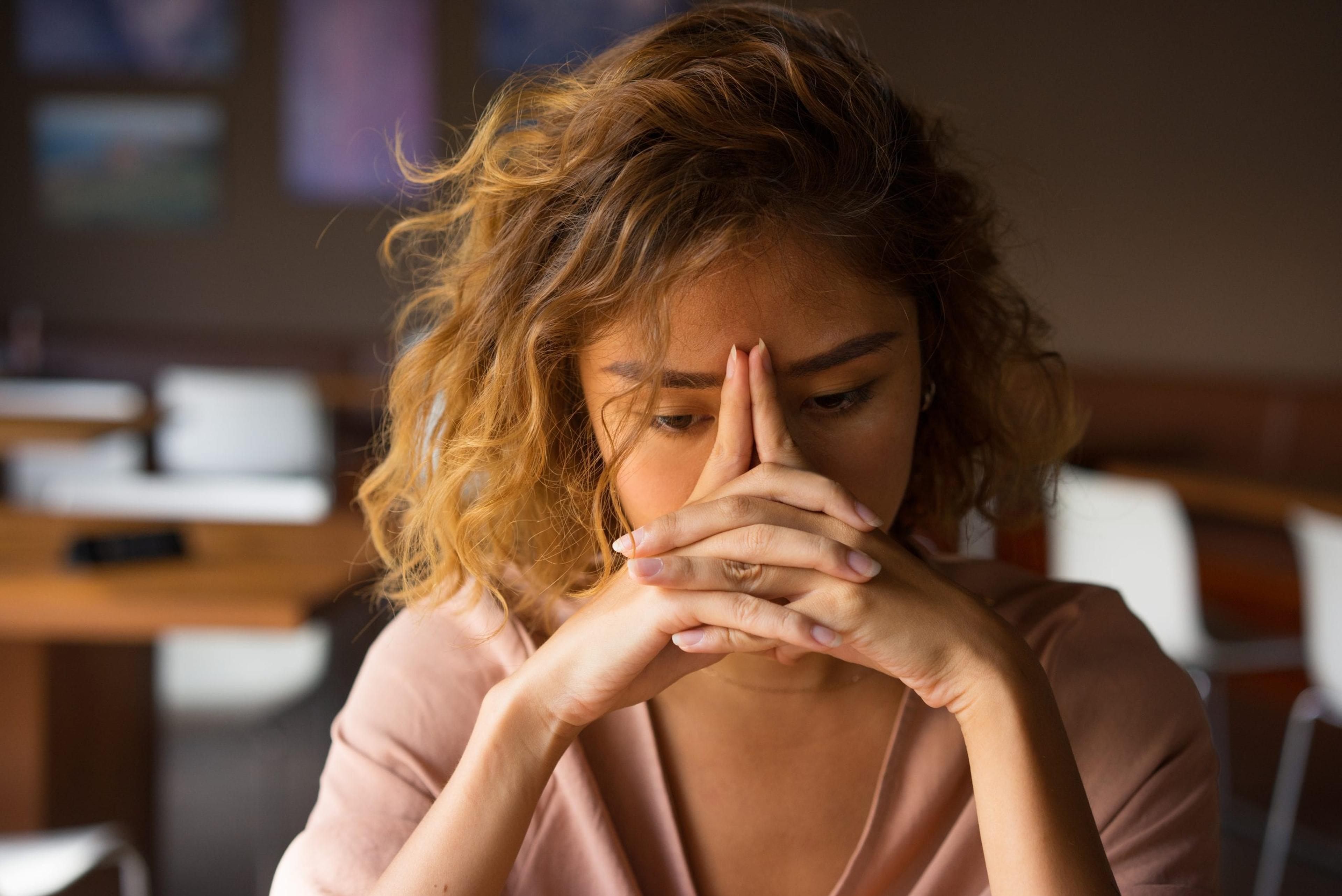 Stressed woman with hands in front of face.
