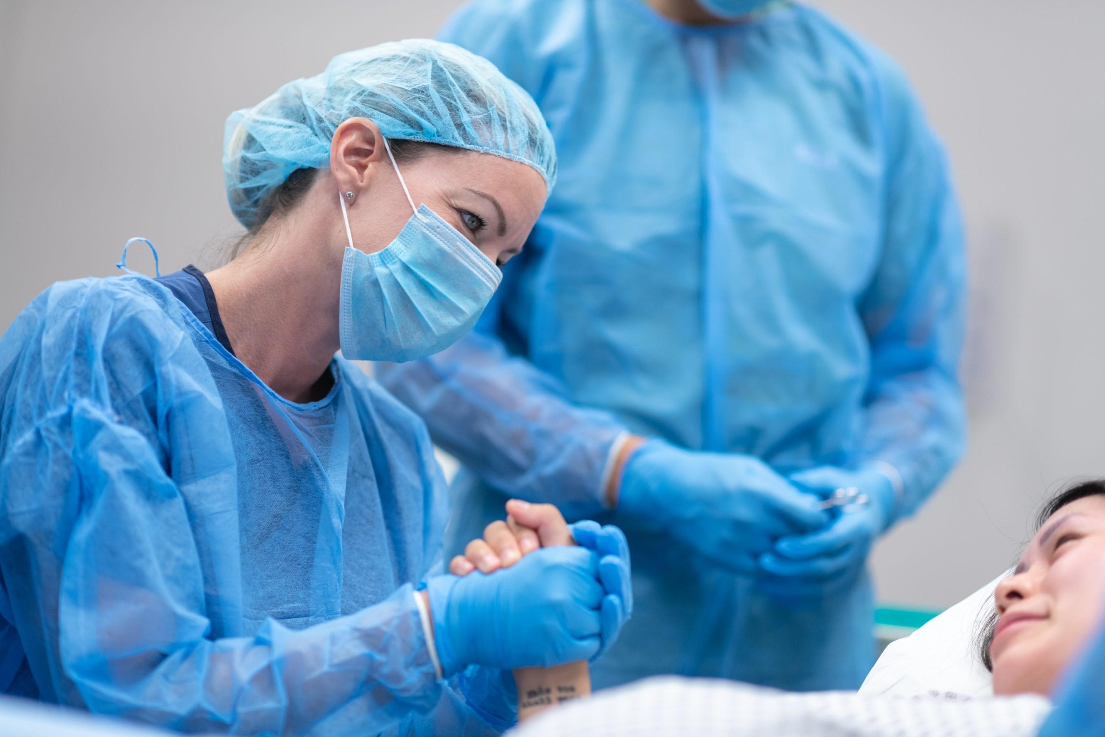 Hospital worker holding the hand of a surgery patient