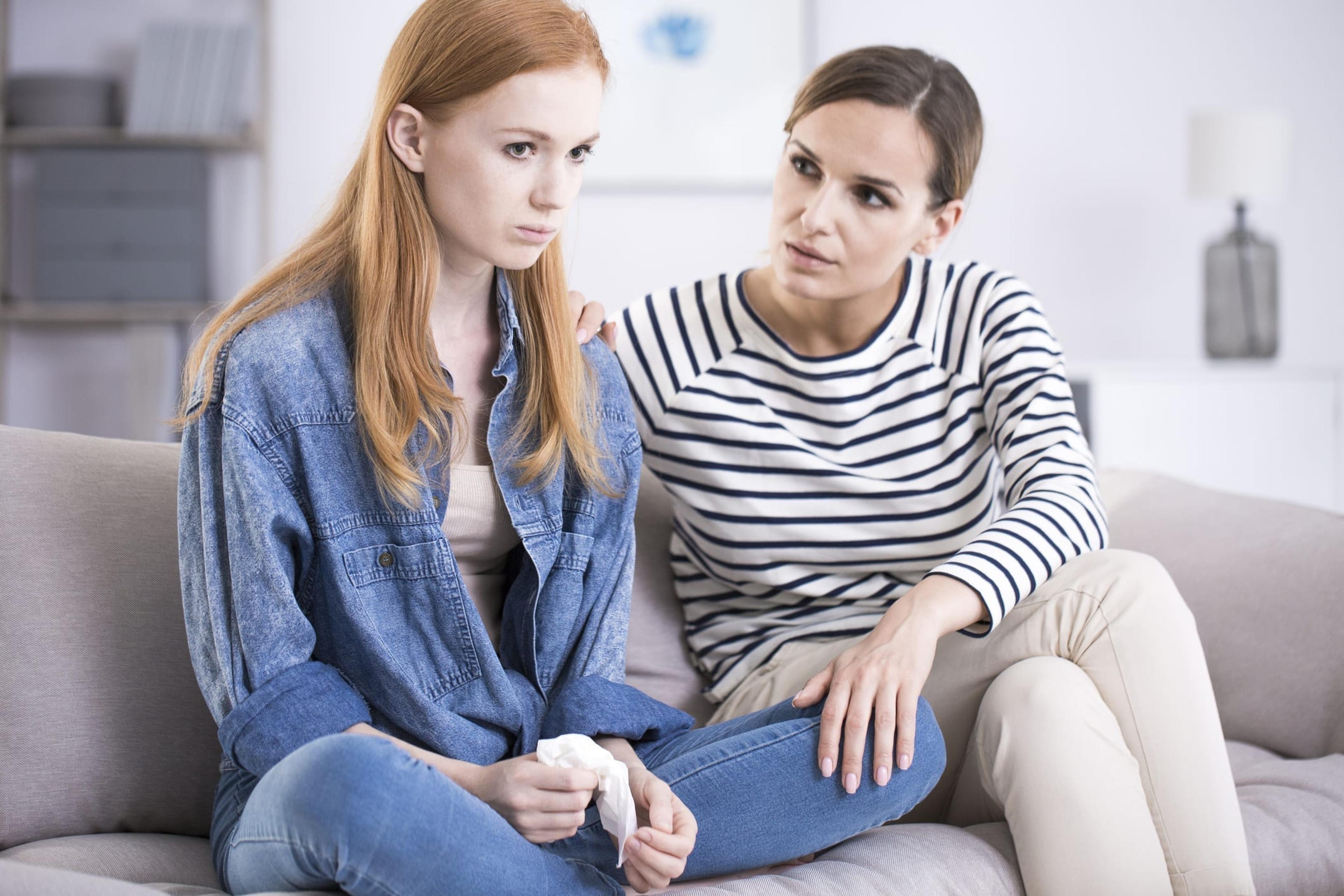 Woman comforting an emotional young teenage girl sitting