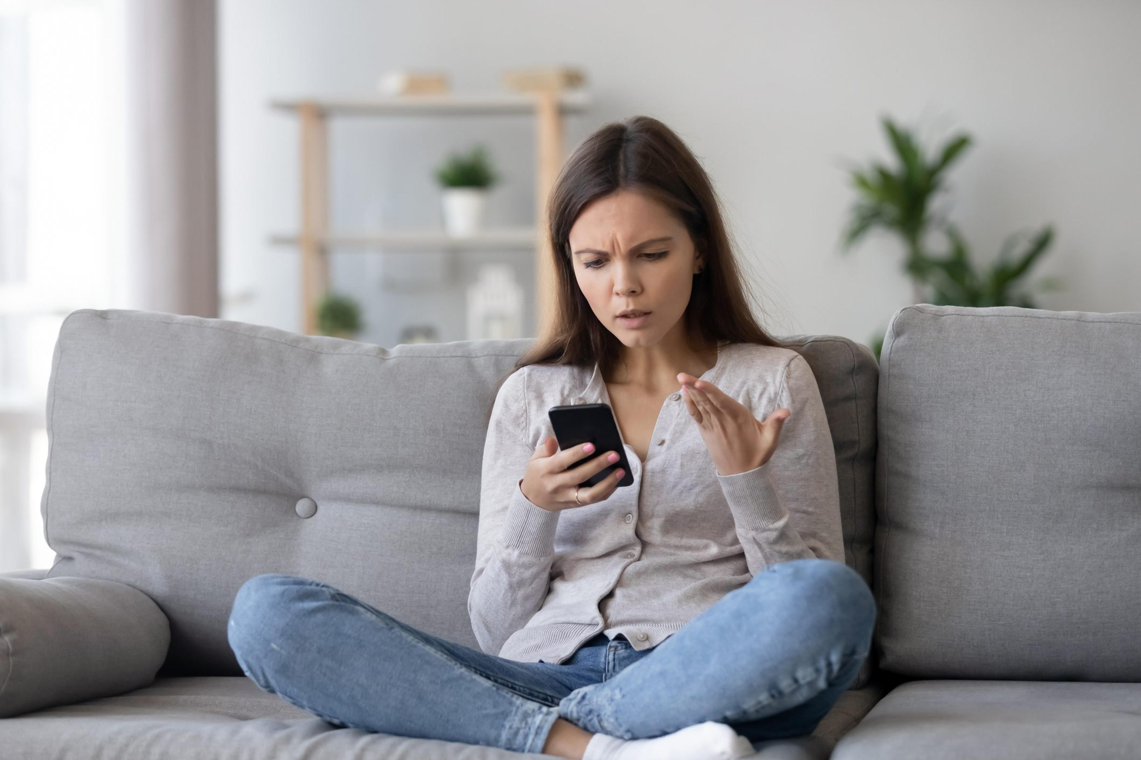 Confused girl feeling upset reading bad news in mobile phone