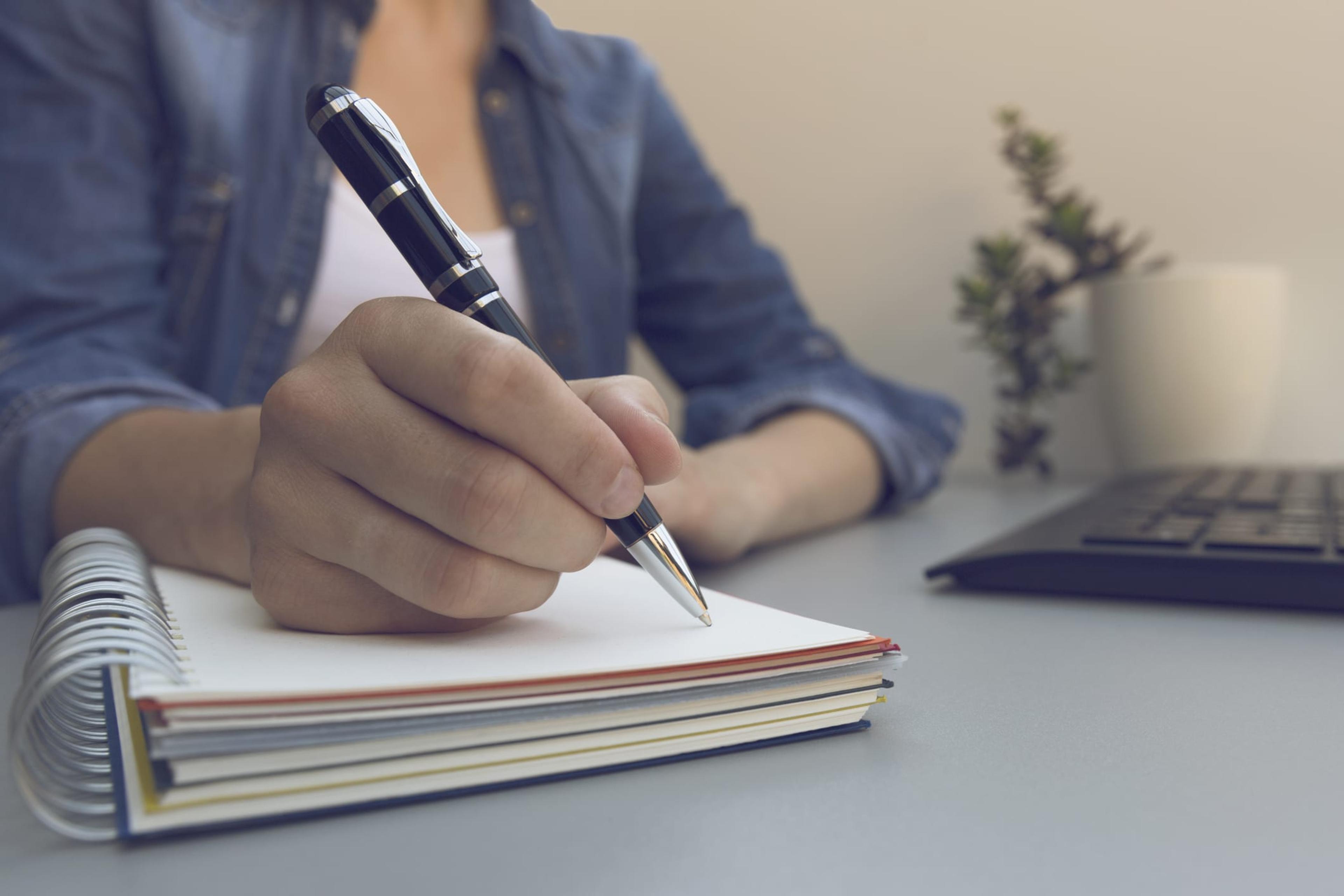 Close-up of woman writing in journal.