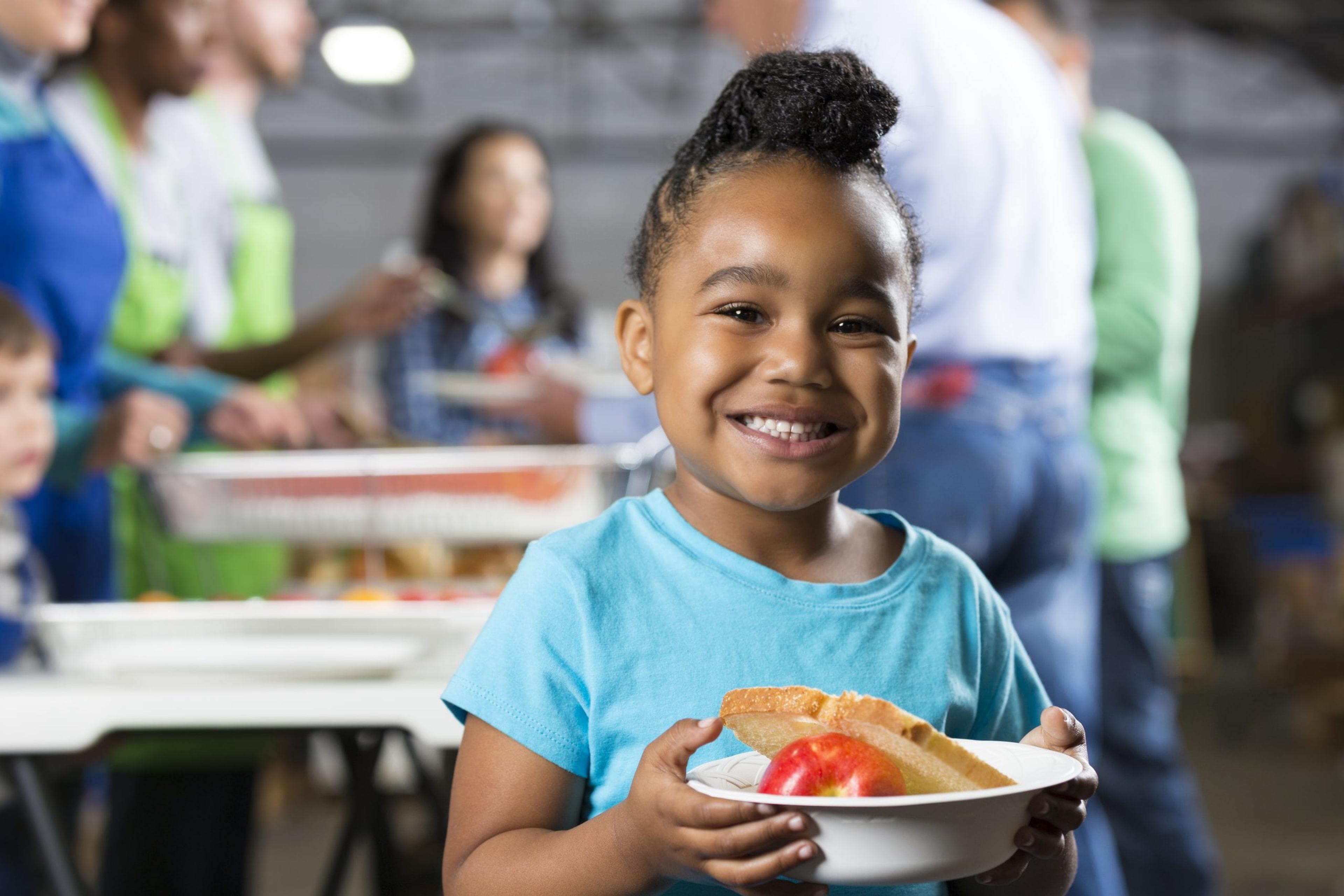 Little girl holding food at a soup kitchen.