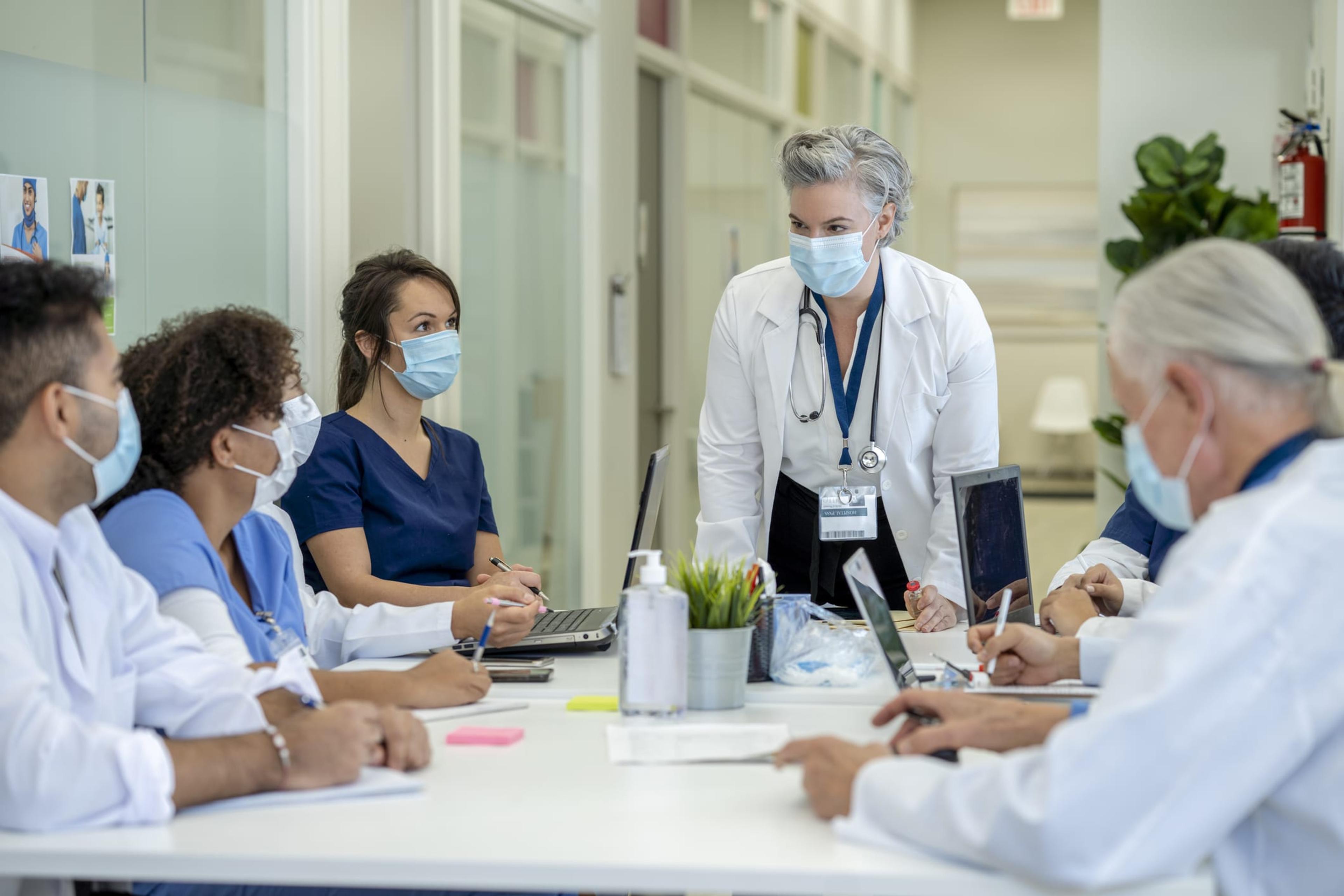 Medical students wearing masks gather at a table