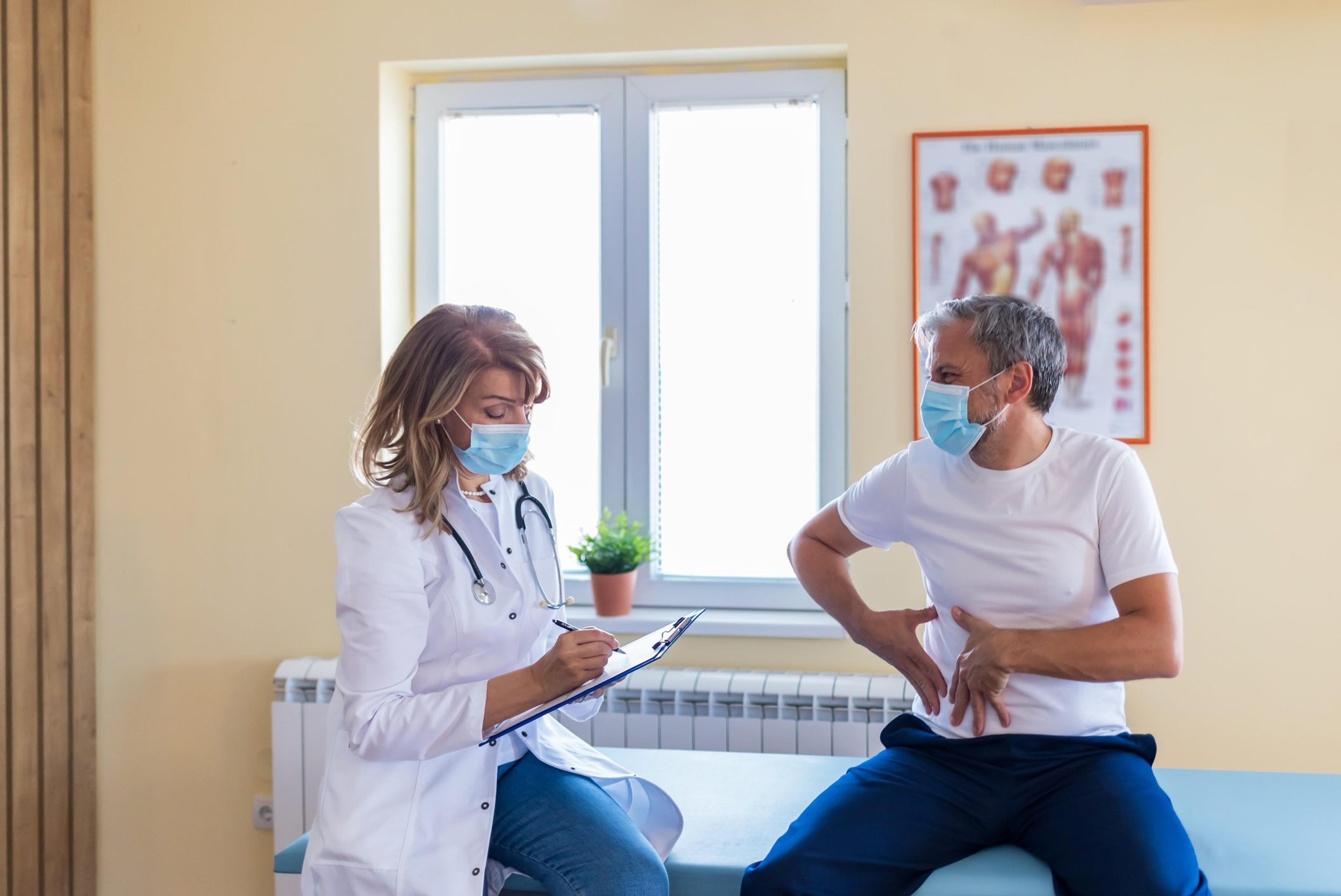 Photo of a female mature doctor with a protective face mask taking anamnesis from her mature patient