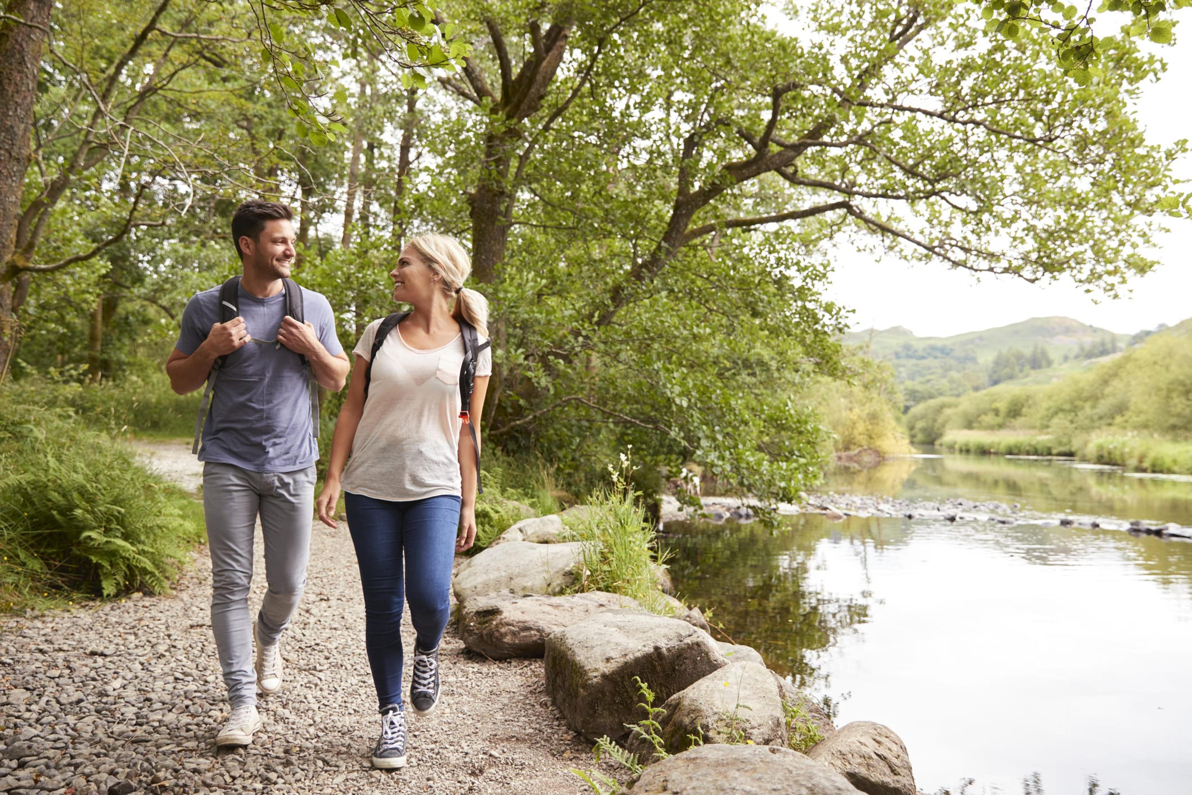 Couple Hiking Along Path By River