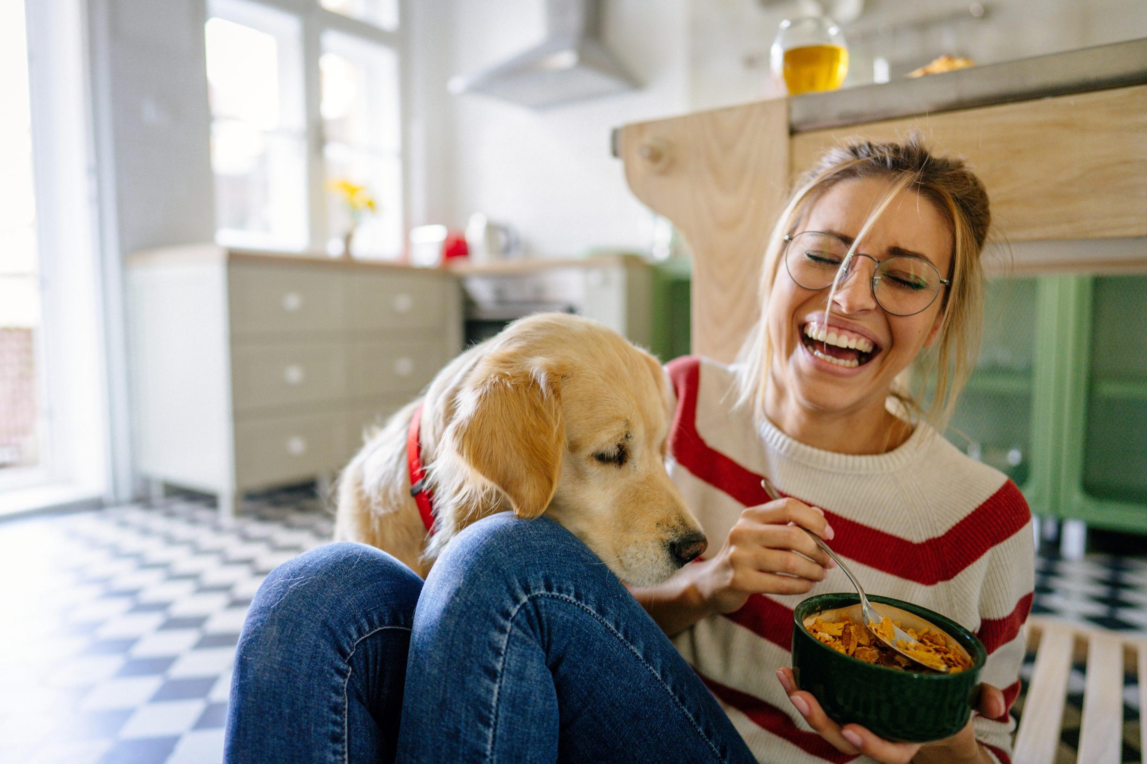 Woman with her dog playing in the kitchen