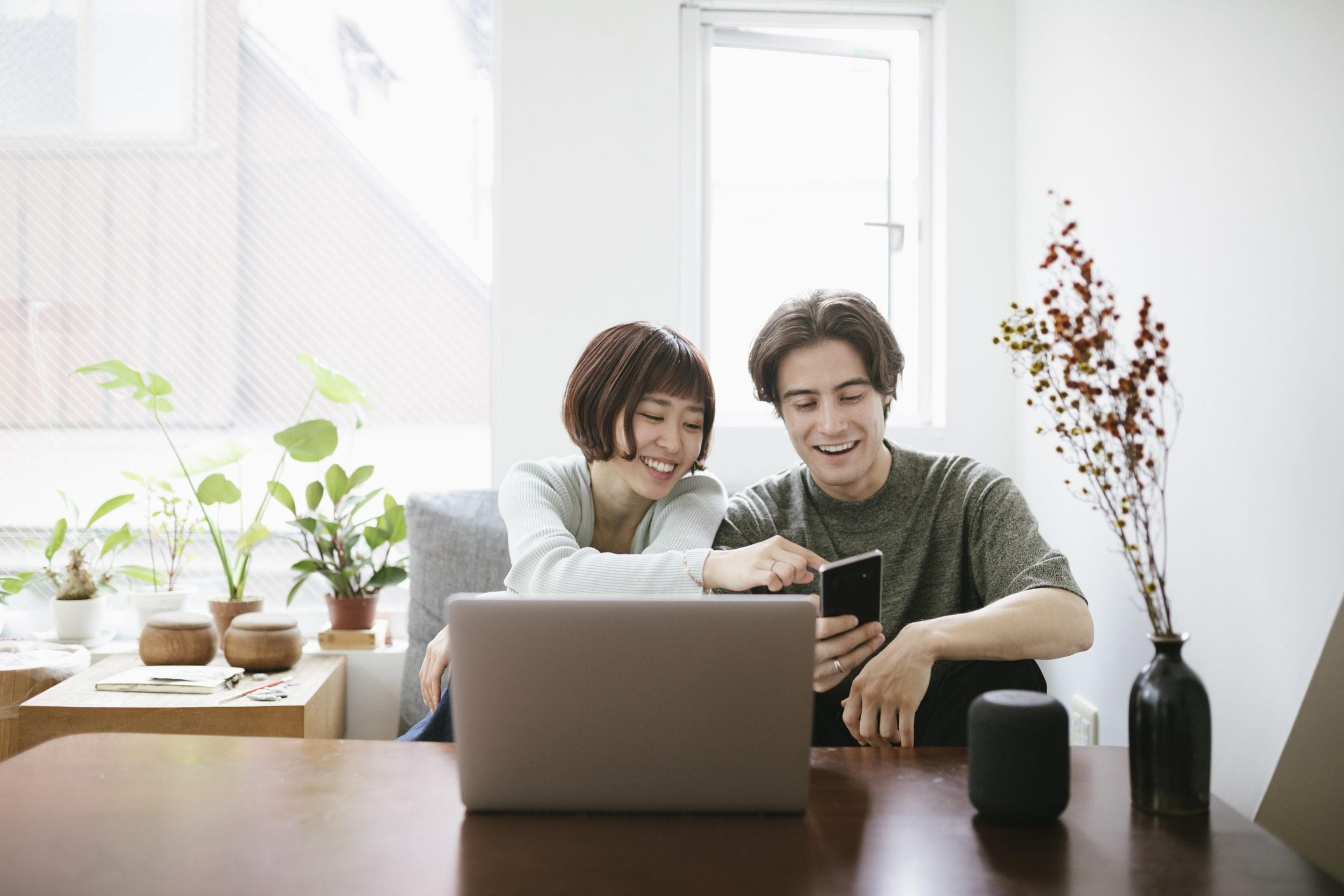 Couple looks at phone sitting on the couch.