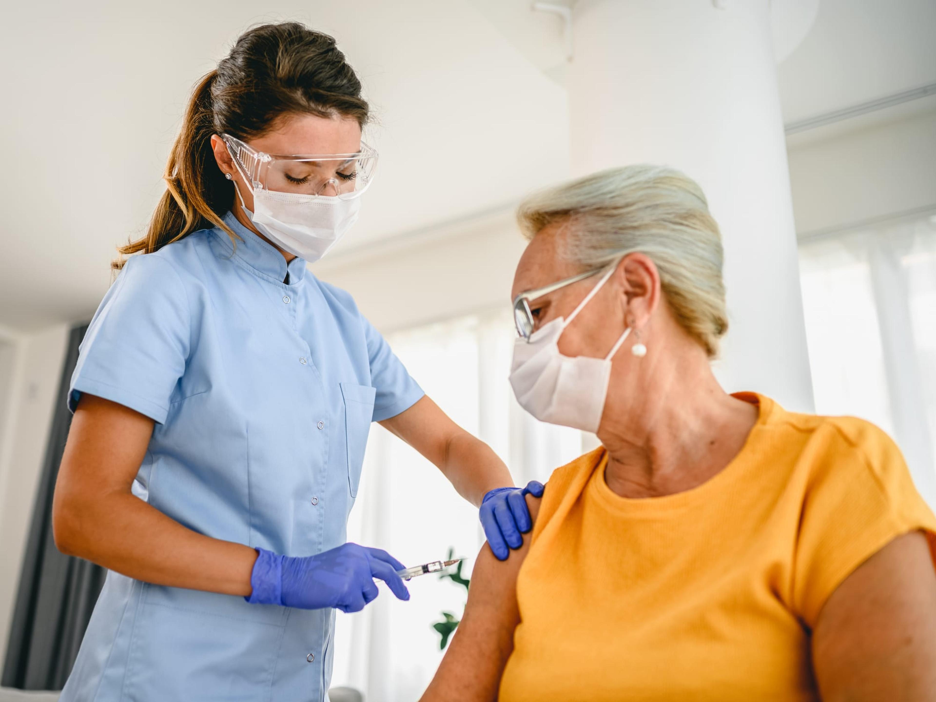 Senior woman wearing a mask receives a COVID-19 vaccine