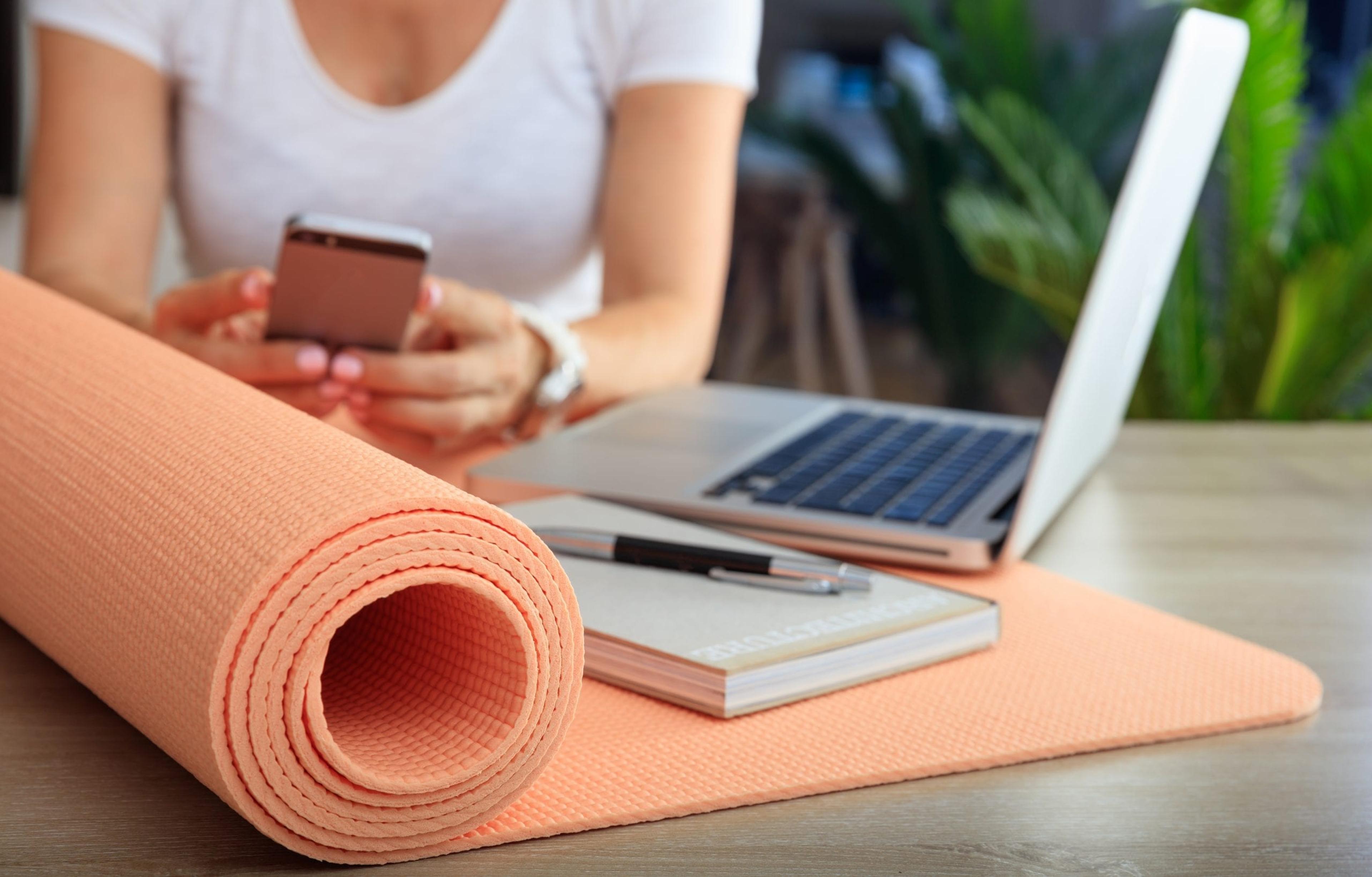 Woman with a laptop and yoga mat