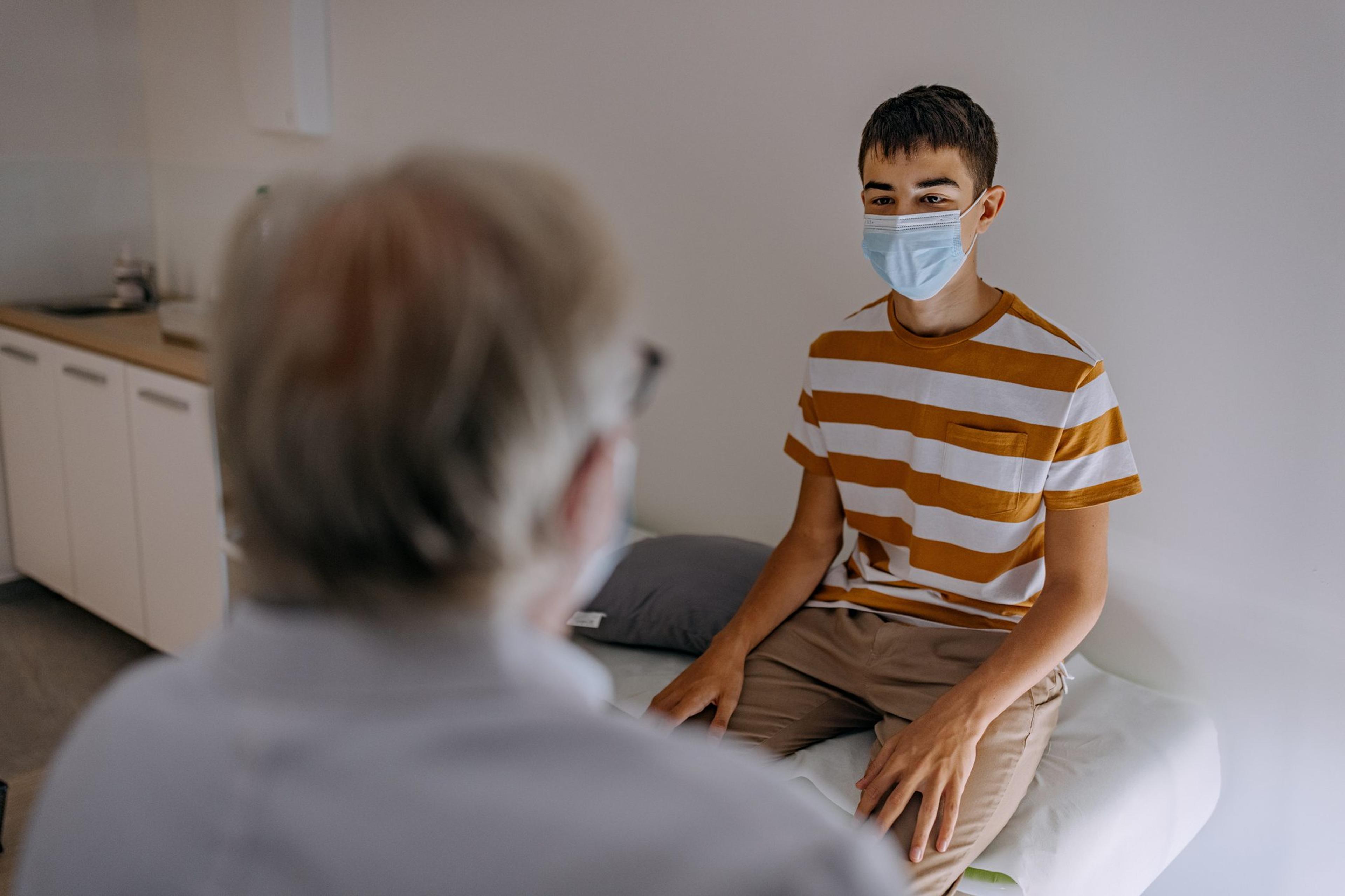 Doctor at hospital wearing mask taking care of young patient
